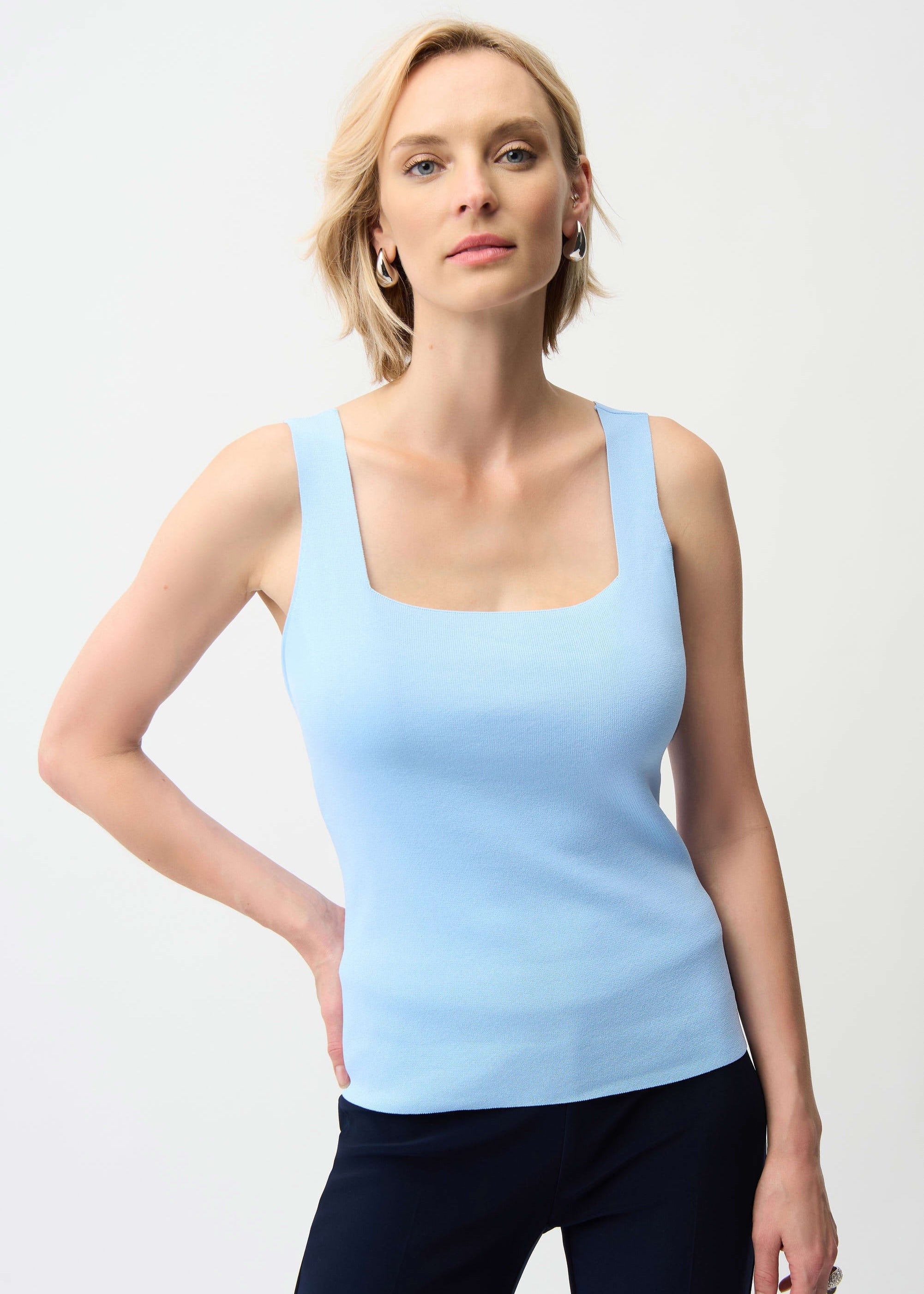 Woman wearing a light blue tank top against a white background