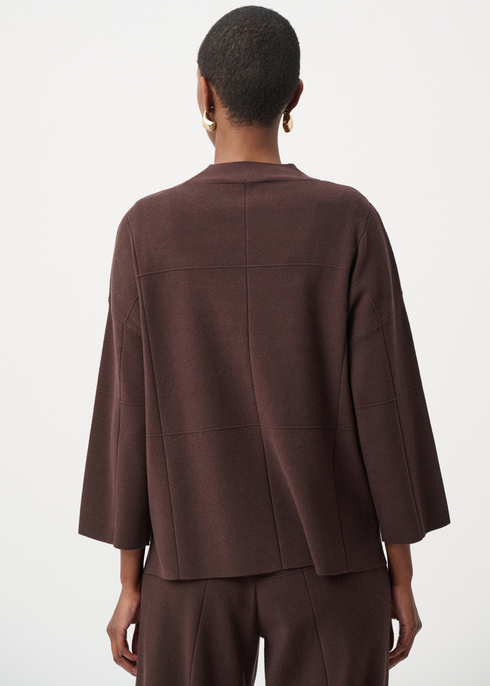 Person wearing a brown jacket and pants on a white background