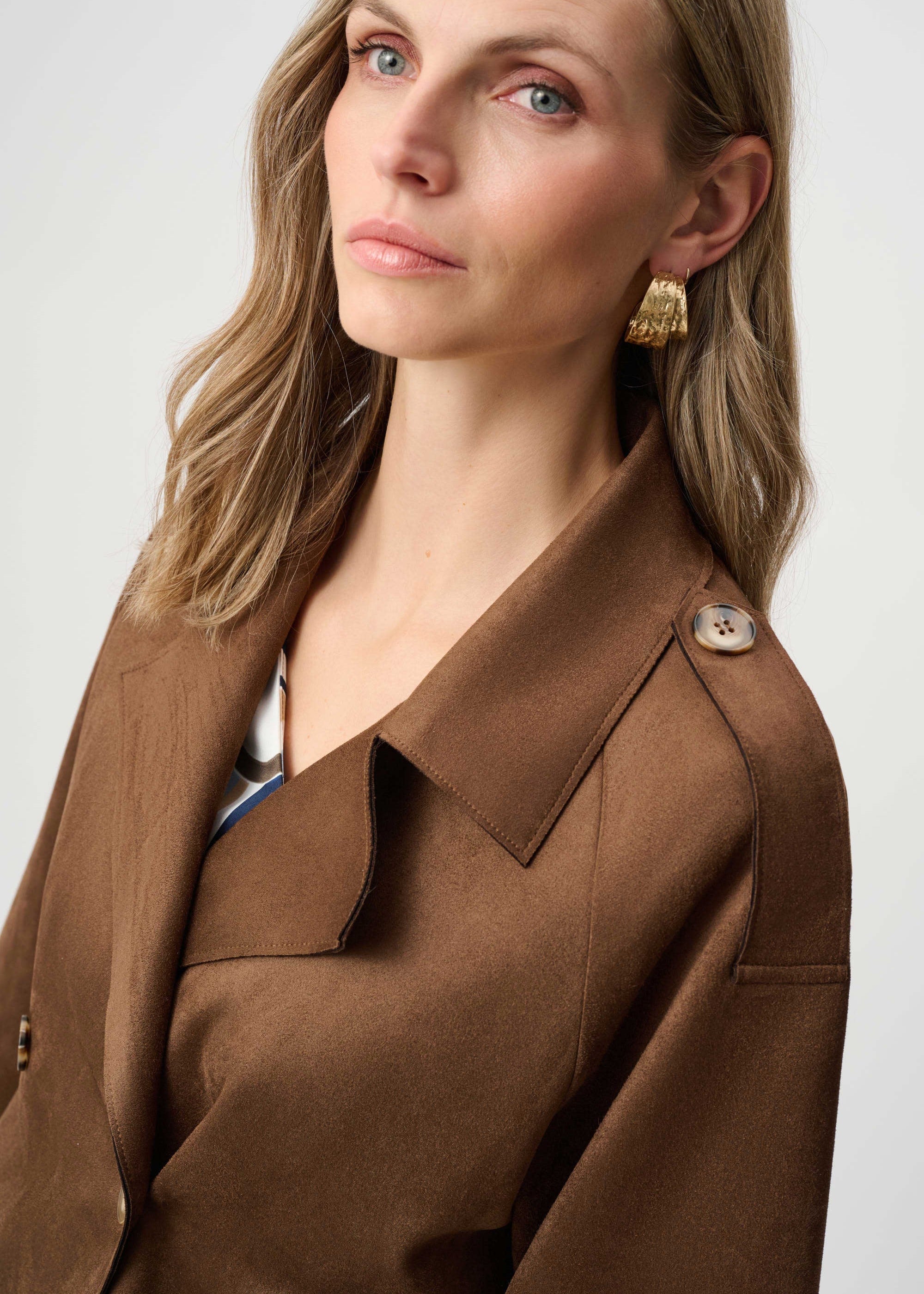 Woman wearing a brown jacket with a plain background