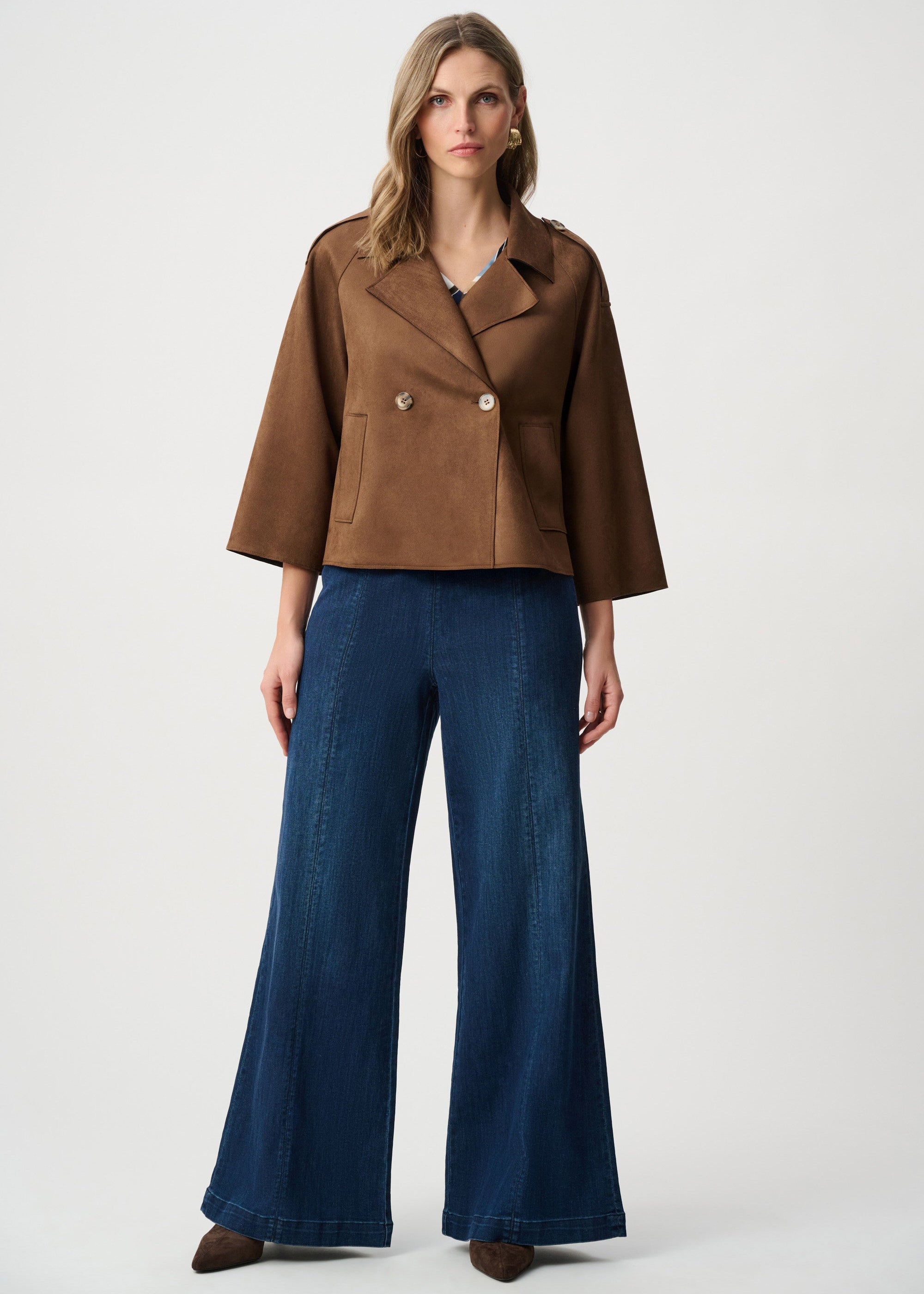 Woman wearing a brown jacket and blue pants on a white background
