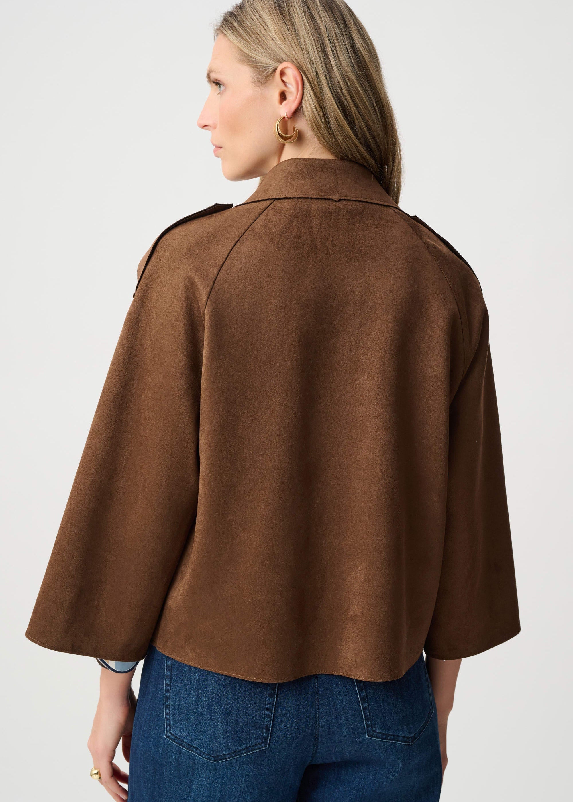 Person wearing a brown jacket and blue jeans on a white background