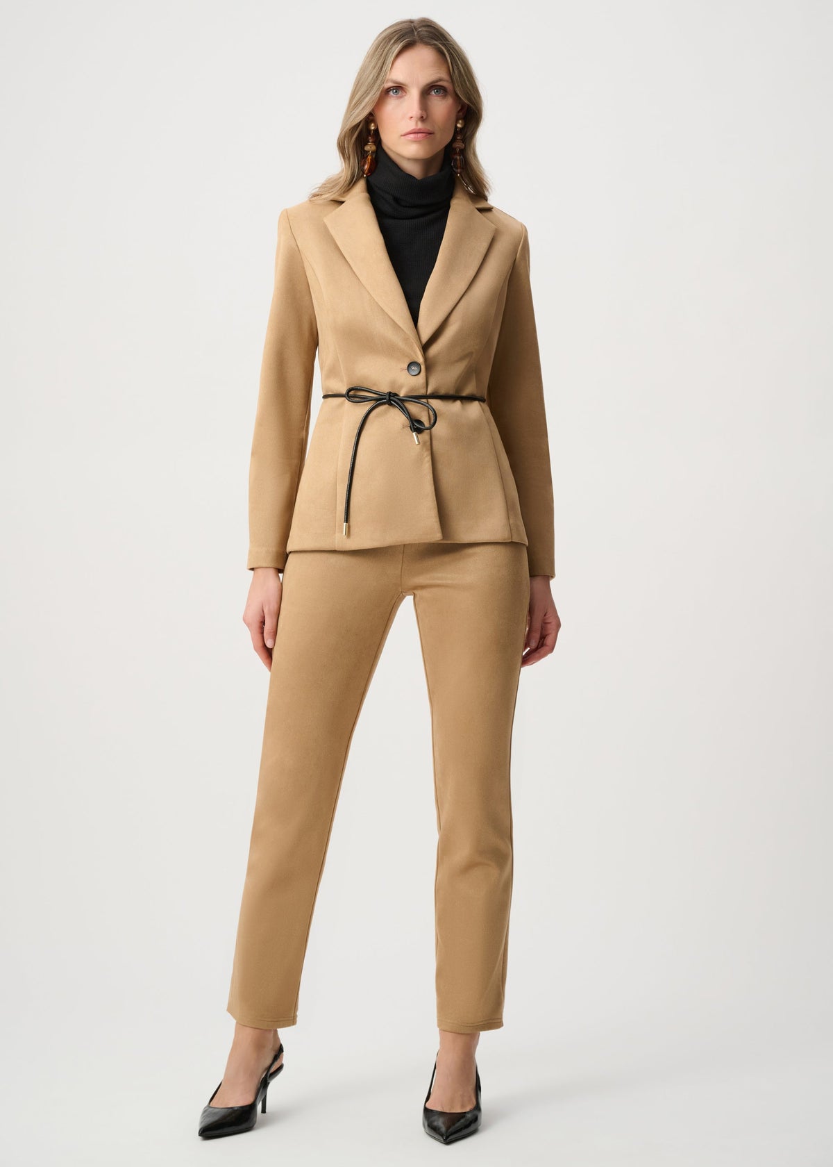 Woman wearing a beige suit with a black top on a white background