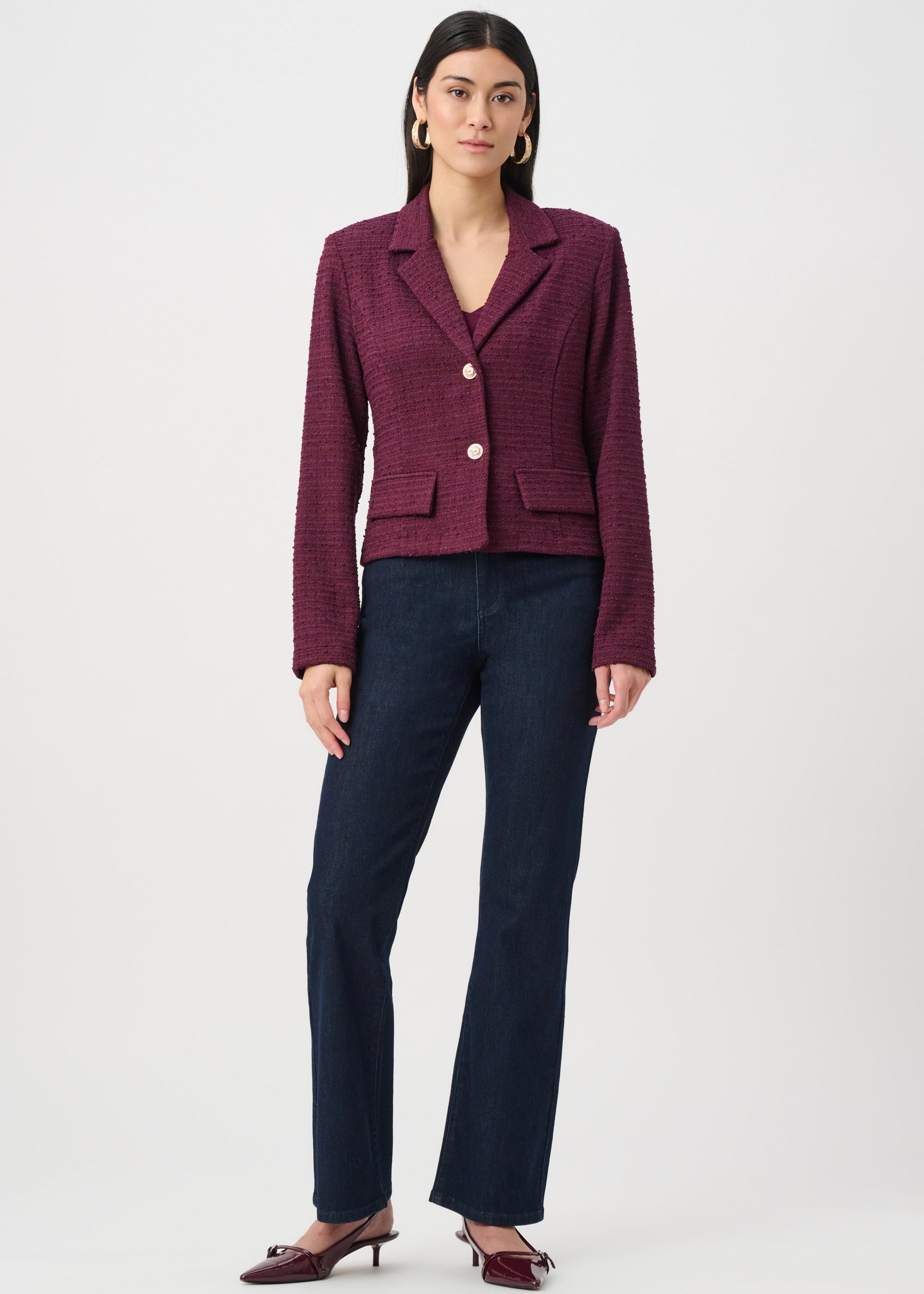 Woman wearing a burgundy blazer and dark blue pants on a white background