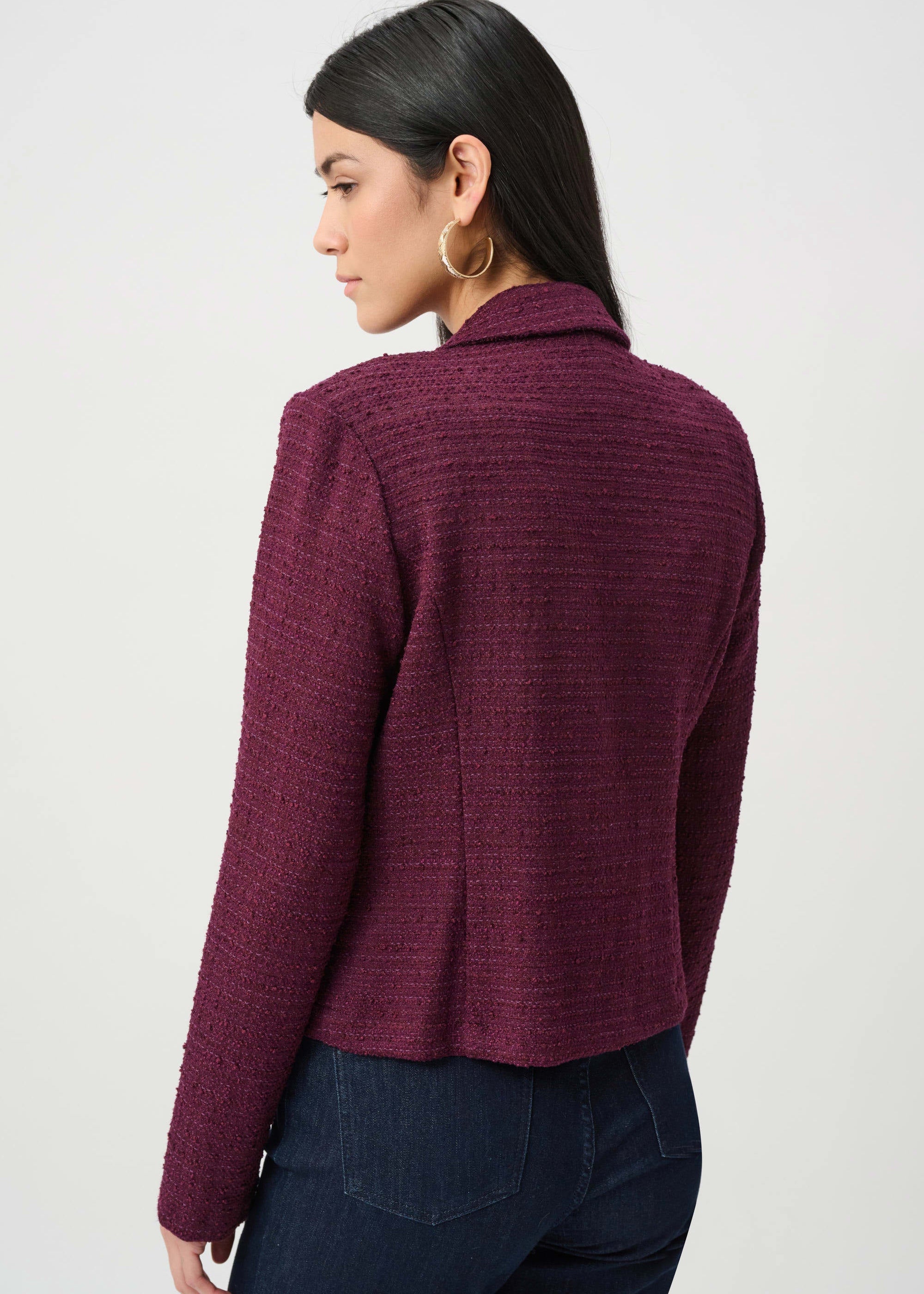 Woman wearing a burgundy textured jacket on a light gray background