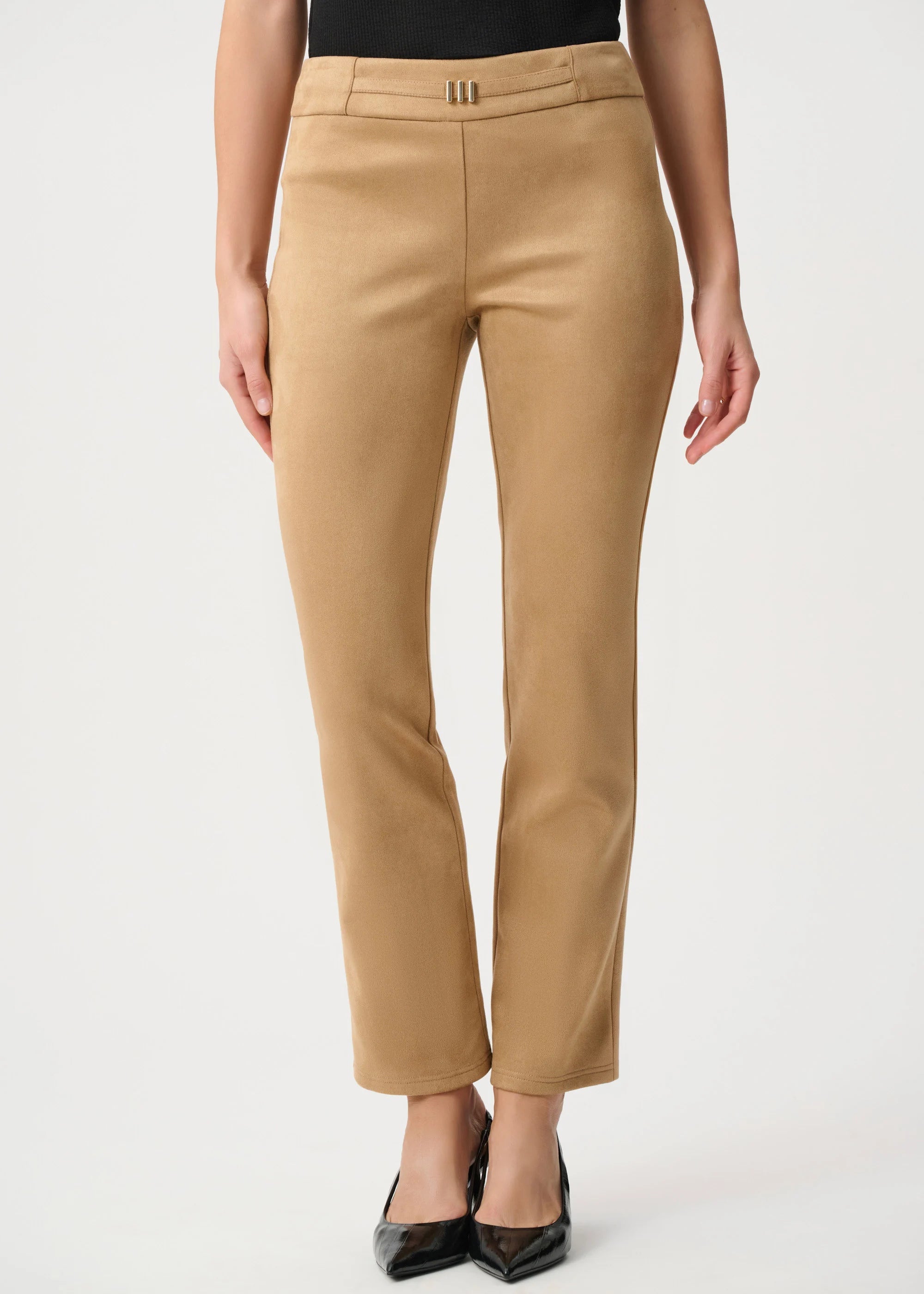 A model wearing a pair of straight-leg cropped trousers in camel tan, paired with a black top and black pointed-toe heels, against a plain light gray studio background.