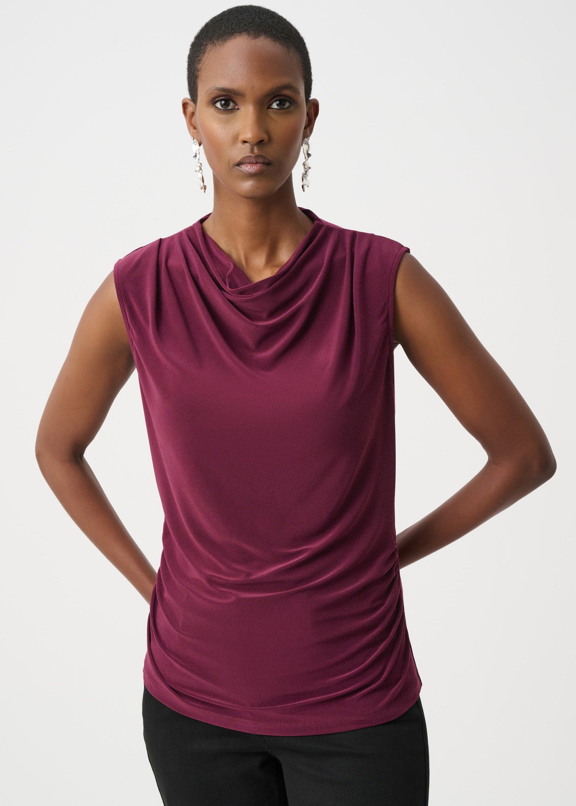 Woman wearing a sleeveless plum-colored top against a white background