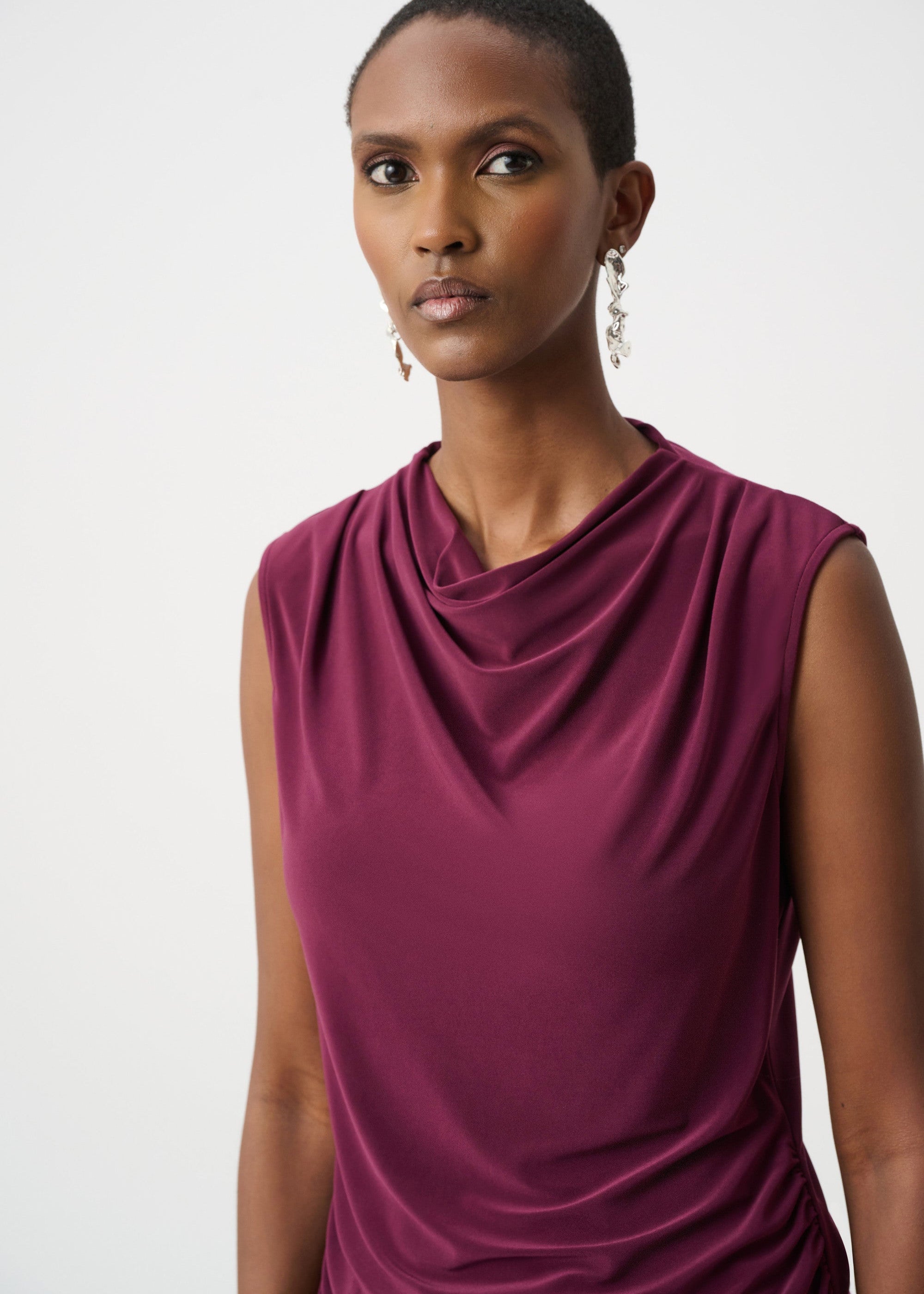Woman wearing a burgundy sleeveless dress against a white background