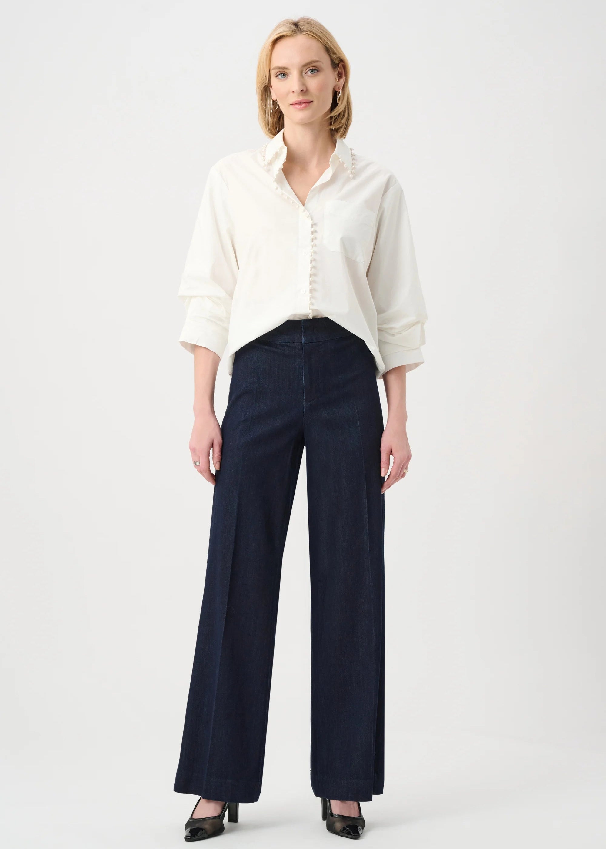 Woman wearing a white blouse and navy pants on a white background