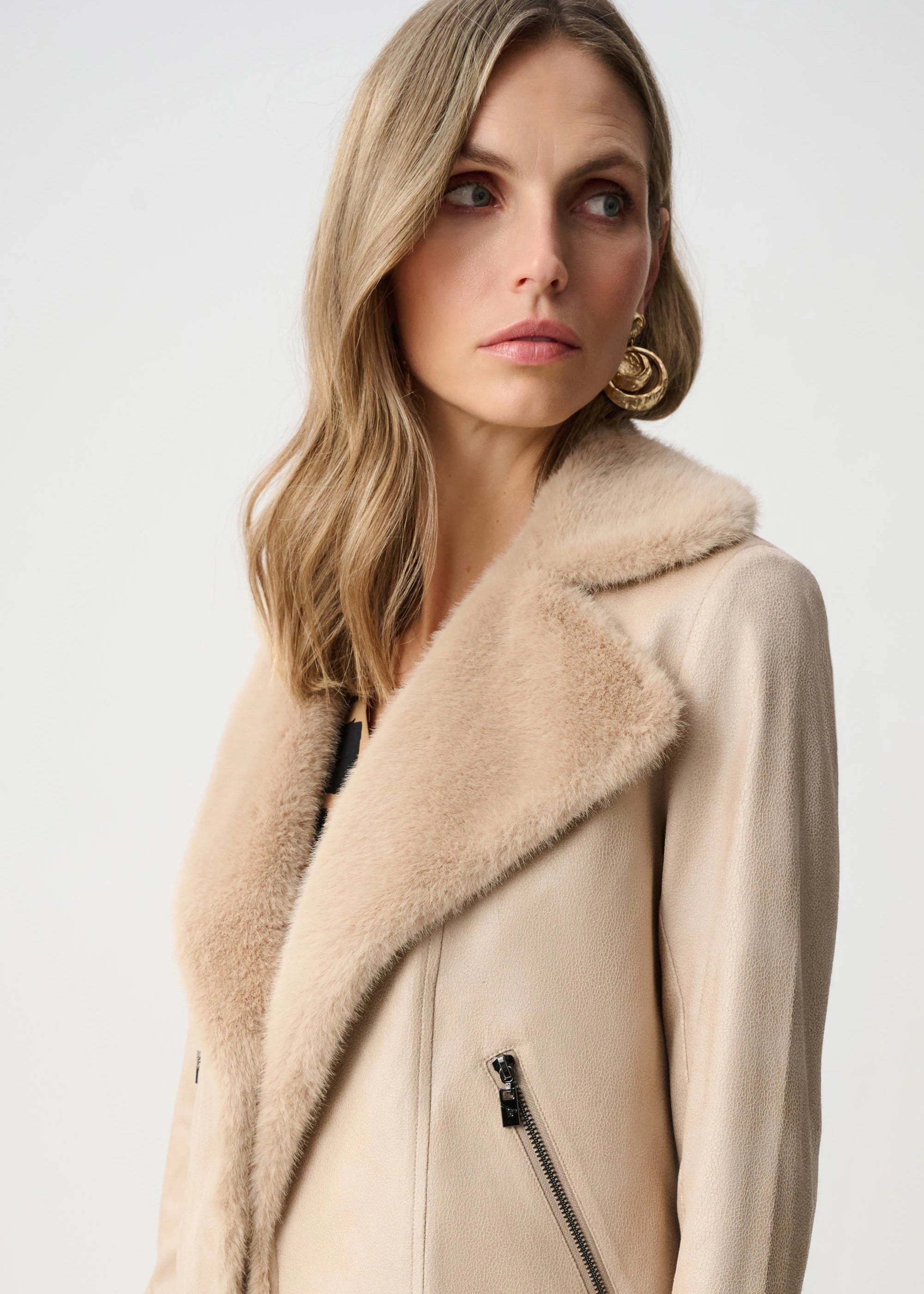 Woman wearing a beige coat with a fur-lined hood on a white background