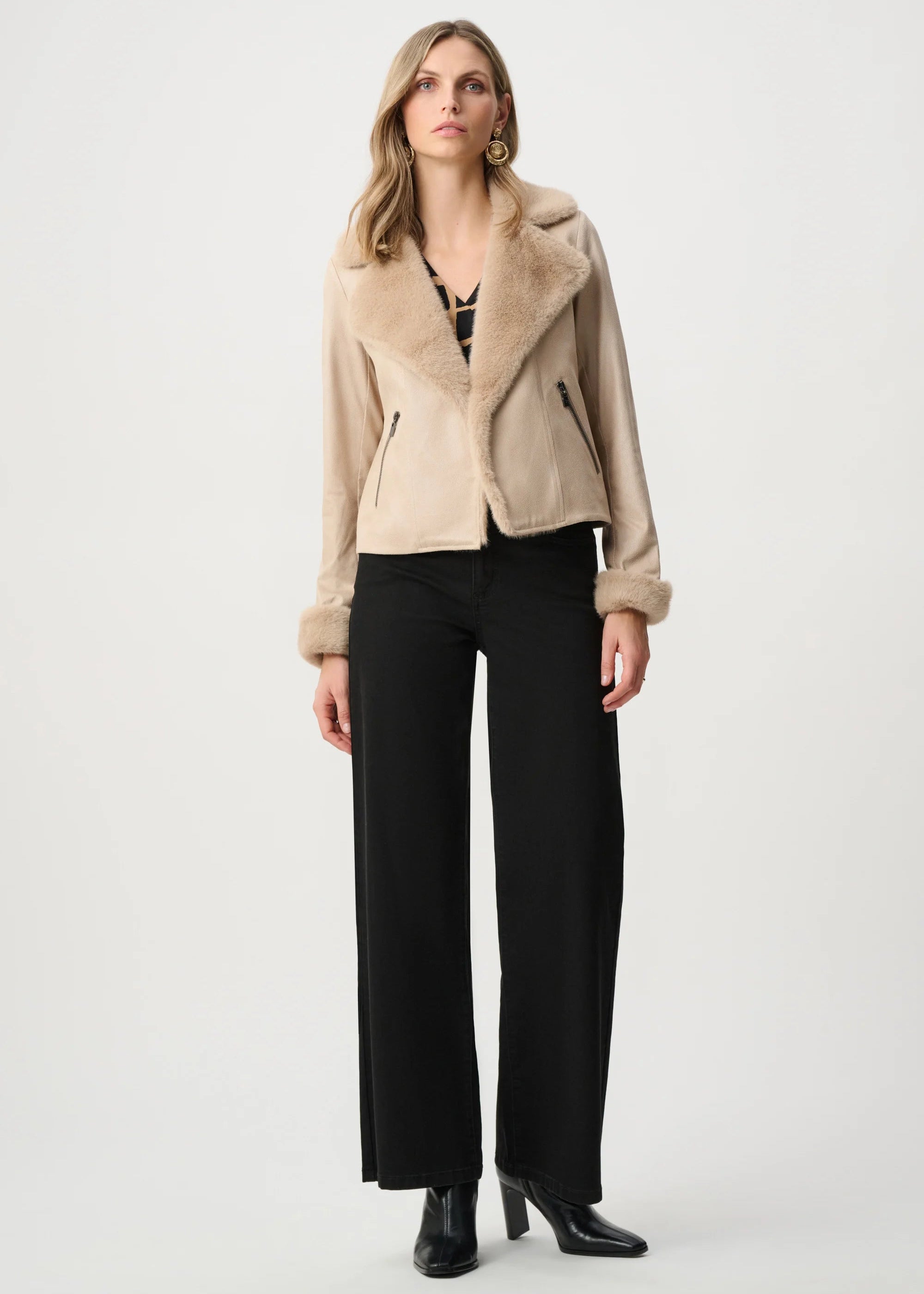 Woman wearing a beige shearling jacket and black pants on a white background