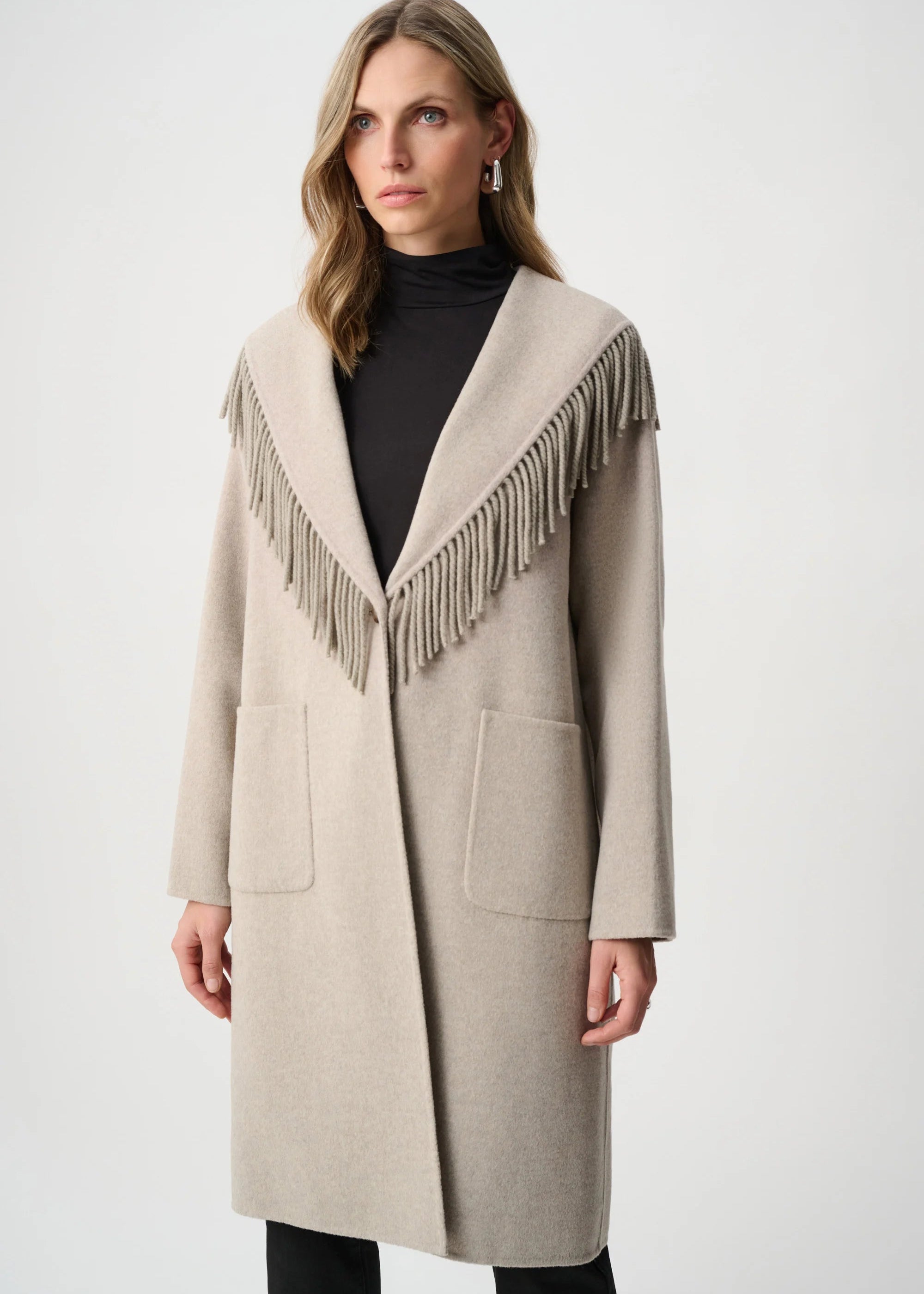 Woman wearing a beige coat with fringe details on a white background