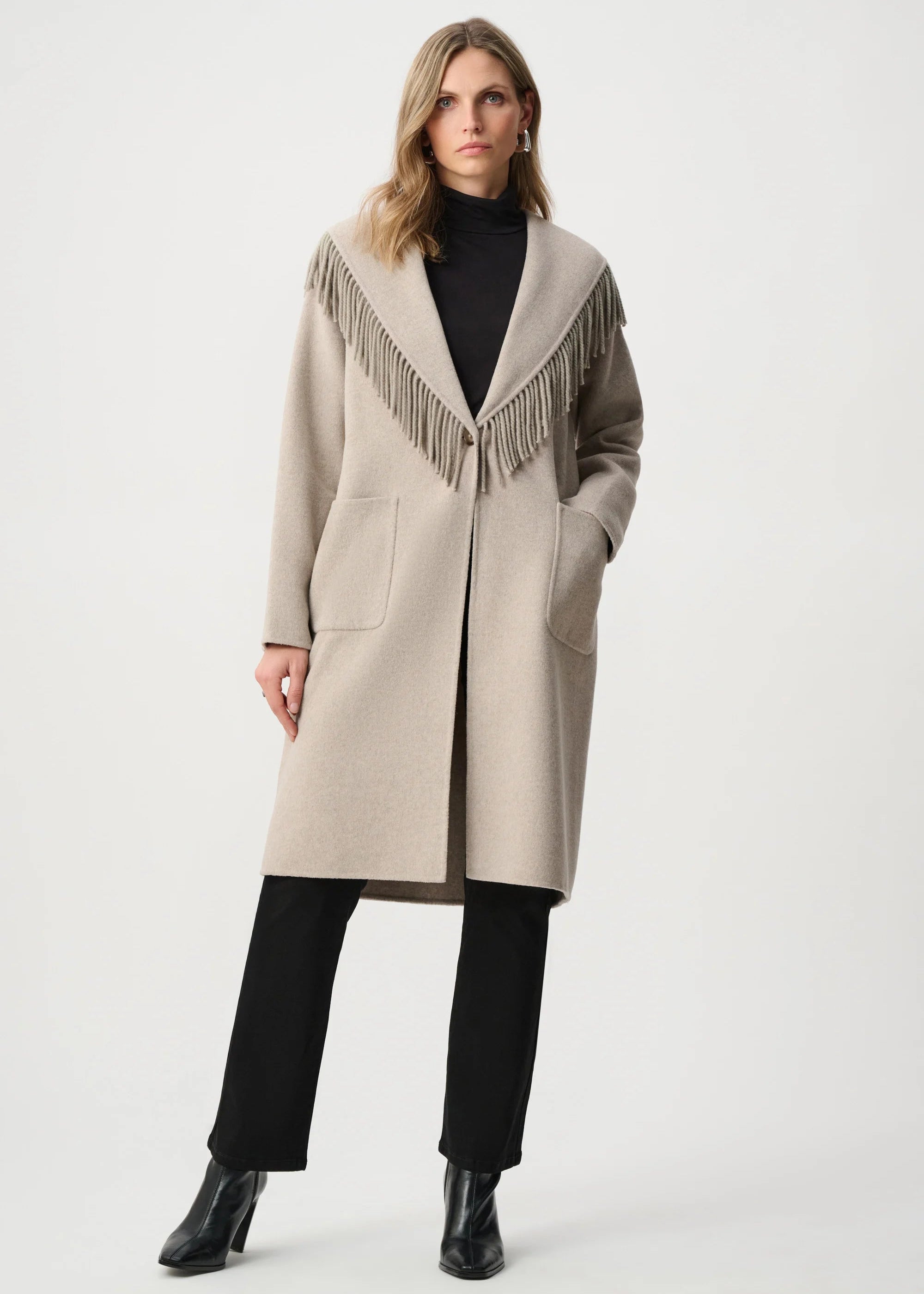 Woman wearing a beige coat with fringe details on a white background