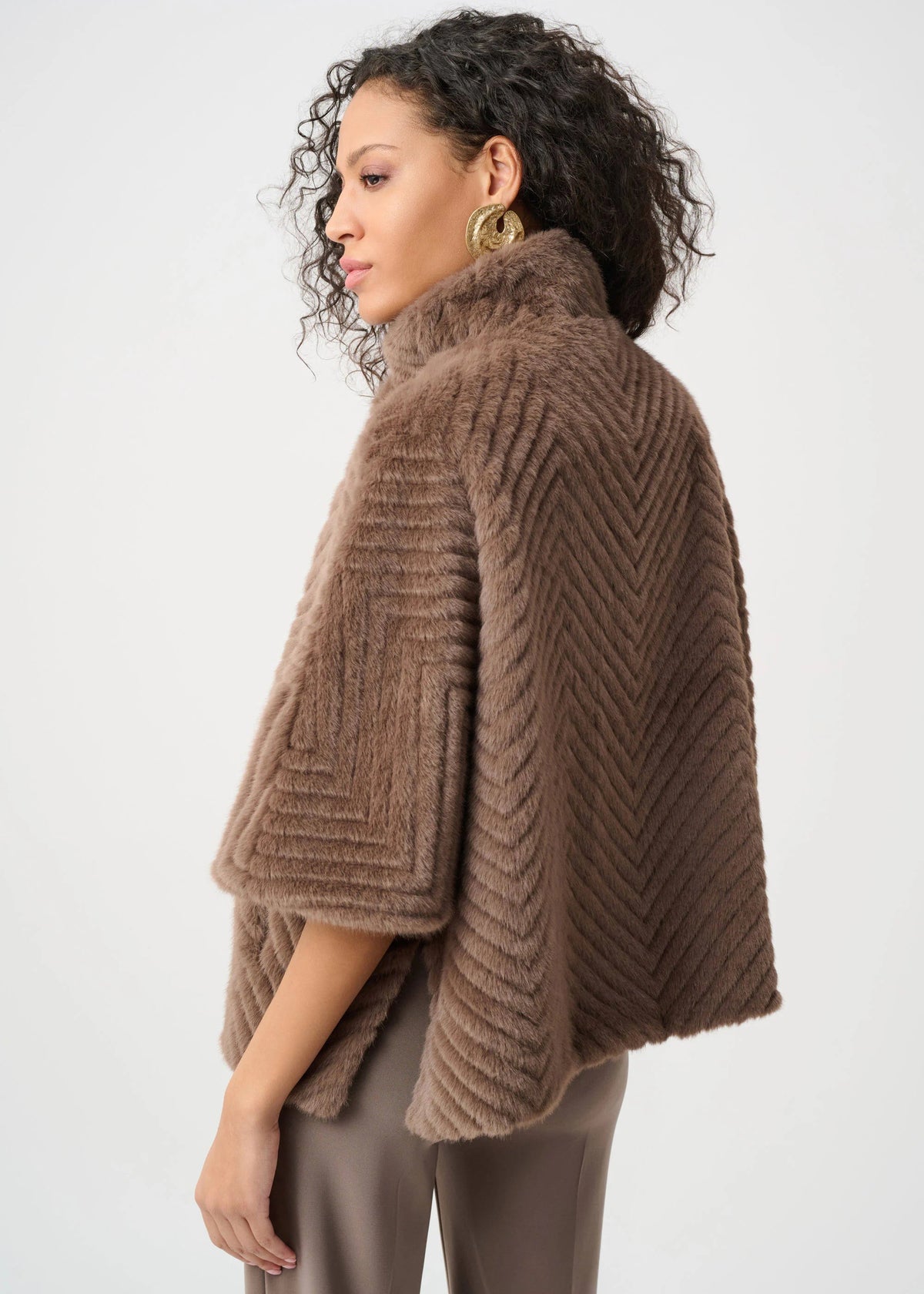 Woman wearing a brown knitted poncho against a white background