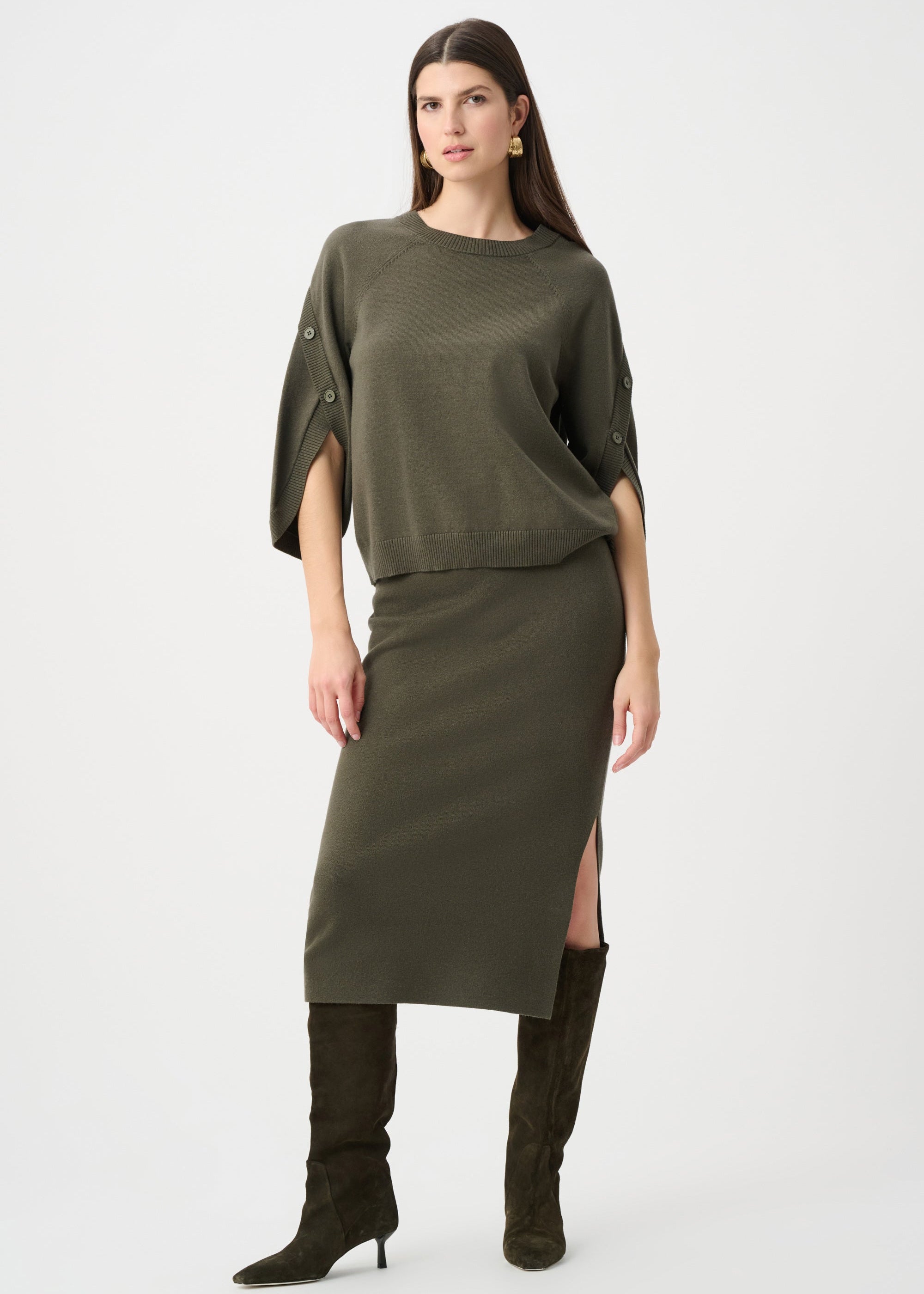 Woman wearing an olive green dress with a slit and matching knee-high boots on a white background