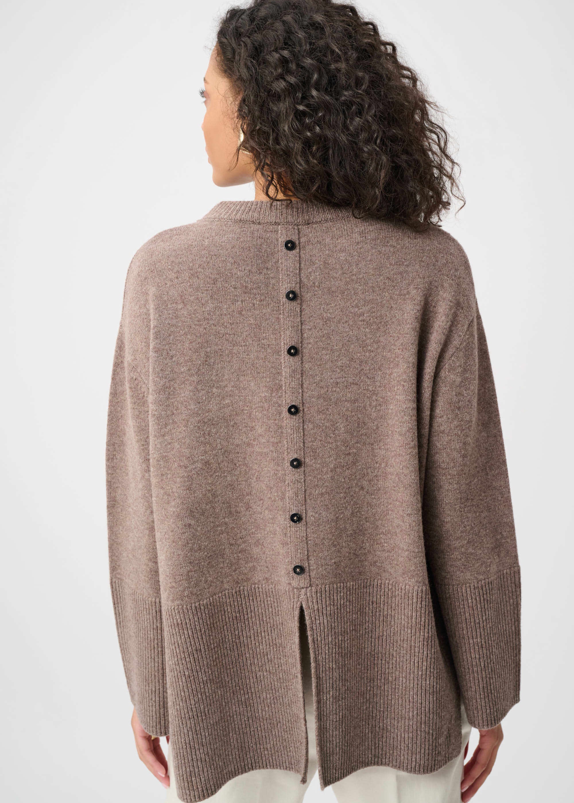 Woman wearing a brown cardigan with black buttons on a white background