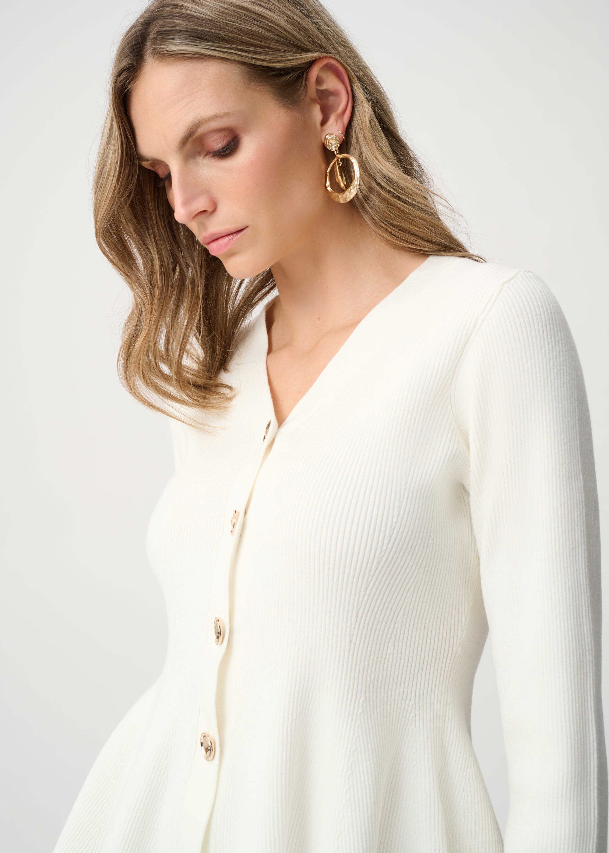 Woman wearing a white cardigan on a plain background