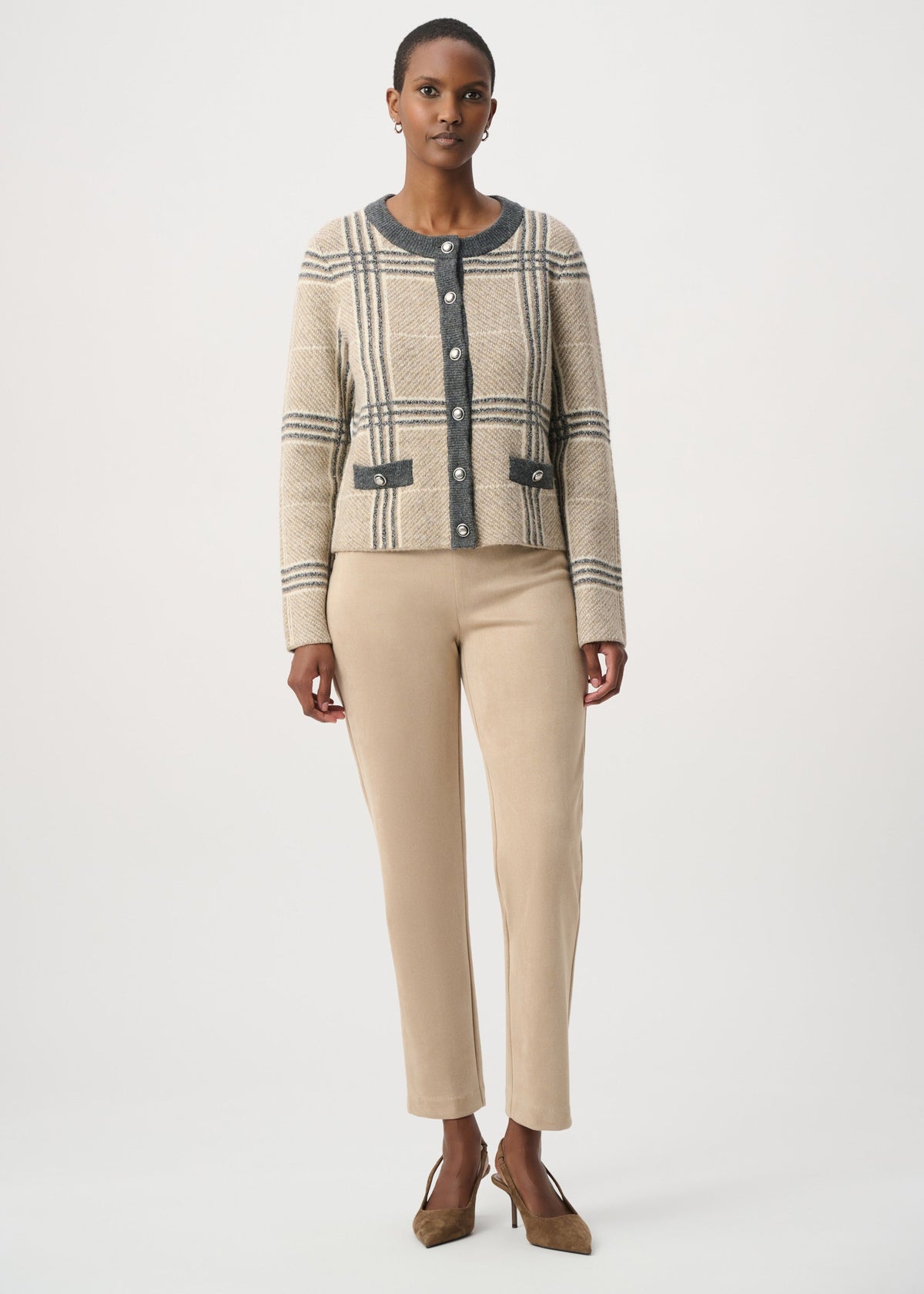 A model stands against a light gray studio background wearing a beige and gray plaid cropped cardigan with dark gray trim, paired with beige cropped trousers and brown pointed-toe heels.