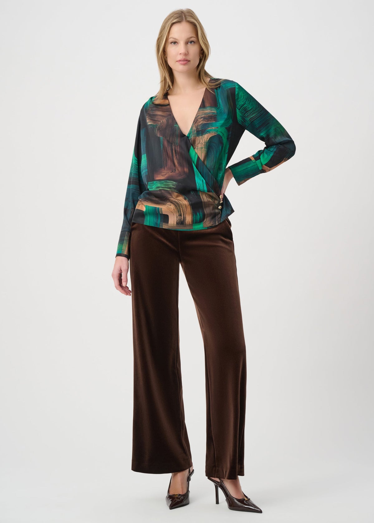 Woman wearing a patterned top and brown pants on a white background