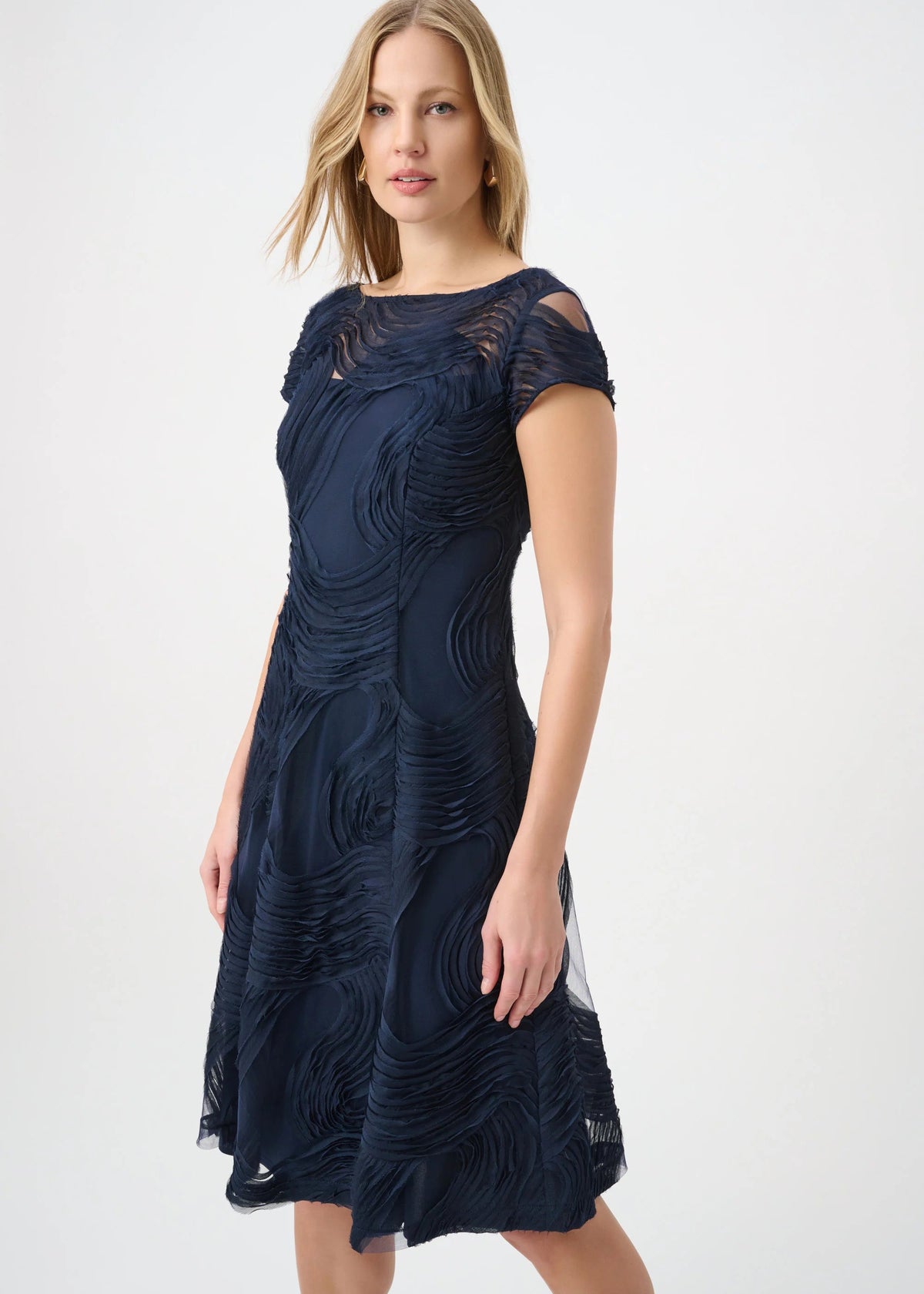 Woman wearing a navy blue dress with intricate patterns on a white background