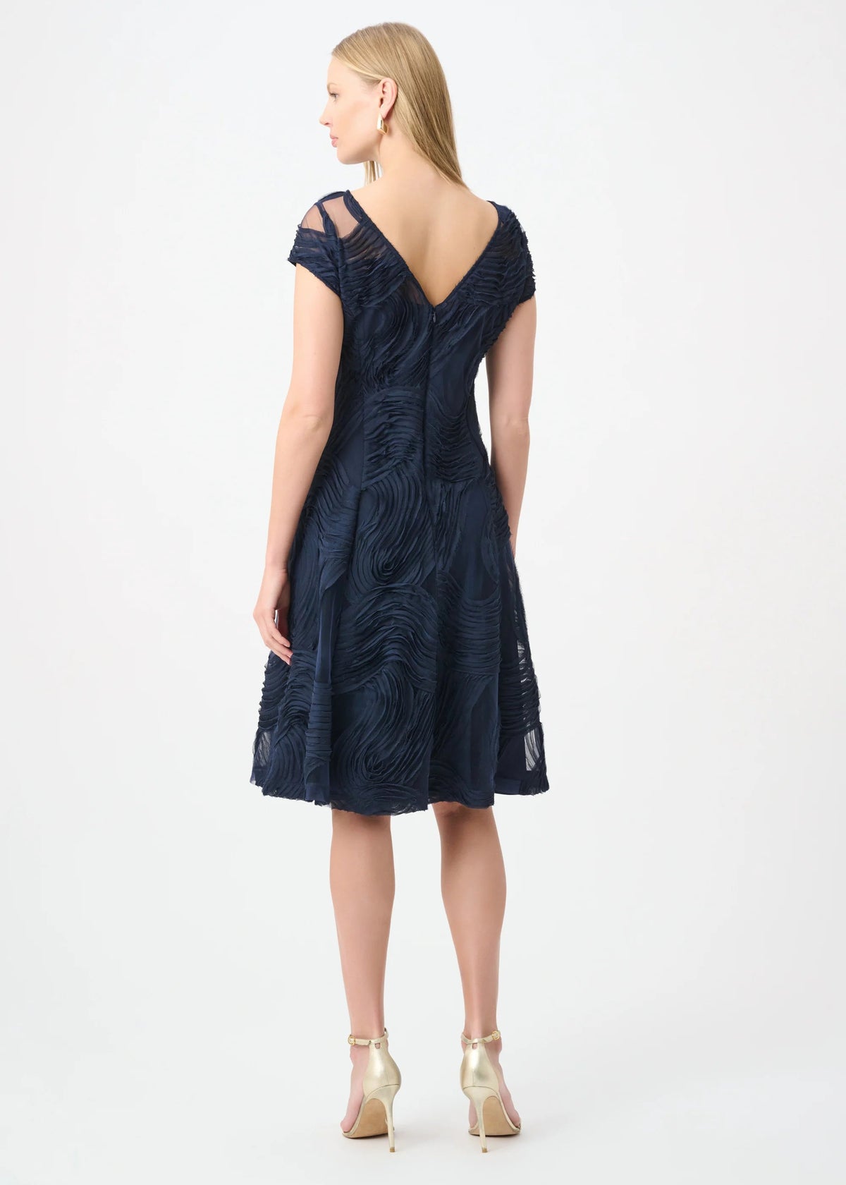 Woman wearing a navy blue dress with cap sleeves on a white background