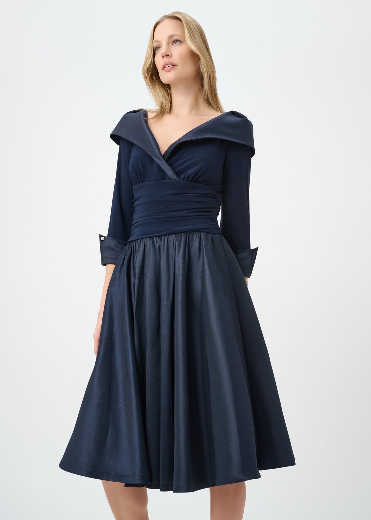Woman wearing a navy blue dress with a hood against a white background