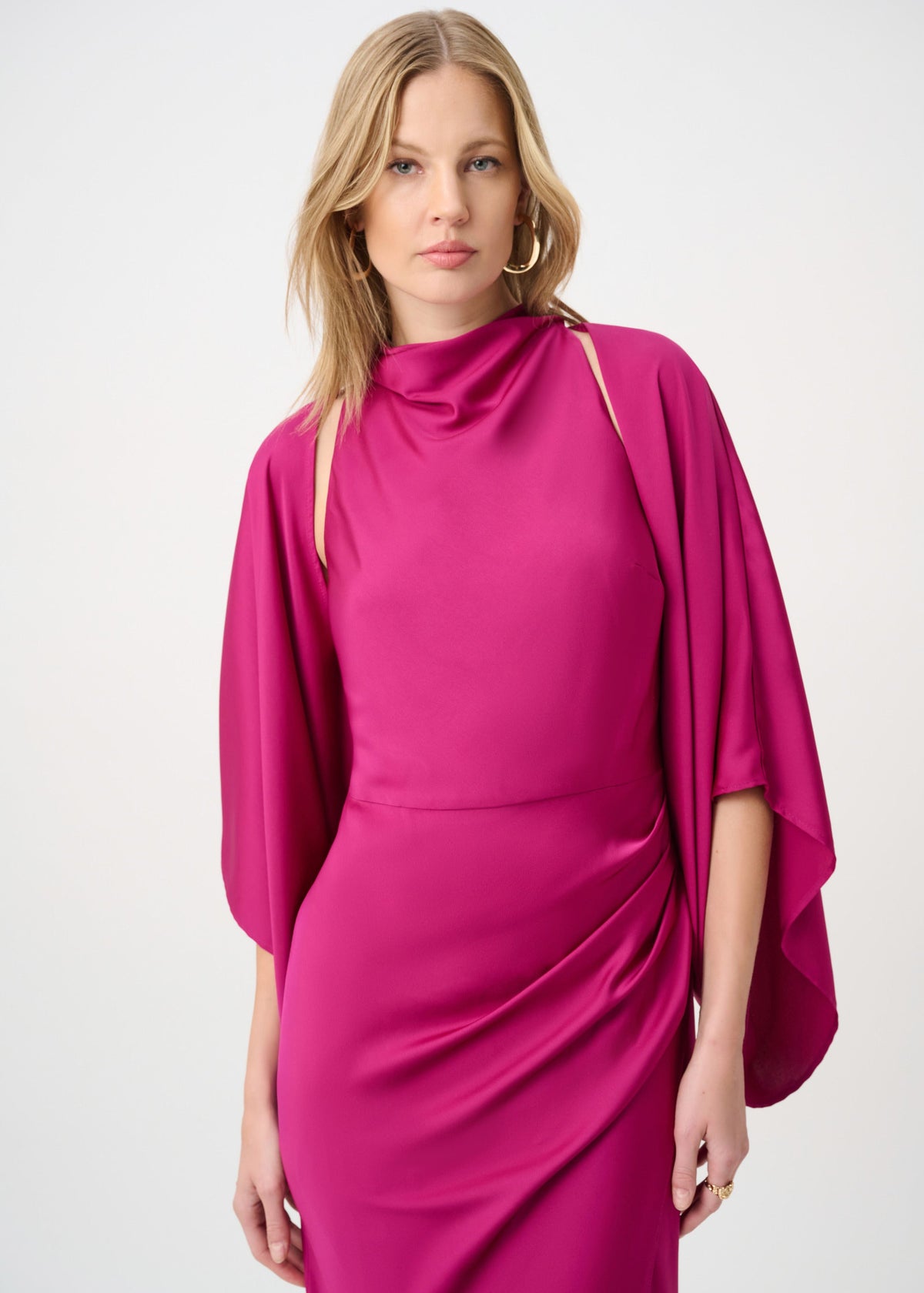 Woman wearing a pink dress with cape sleeves on a white background
