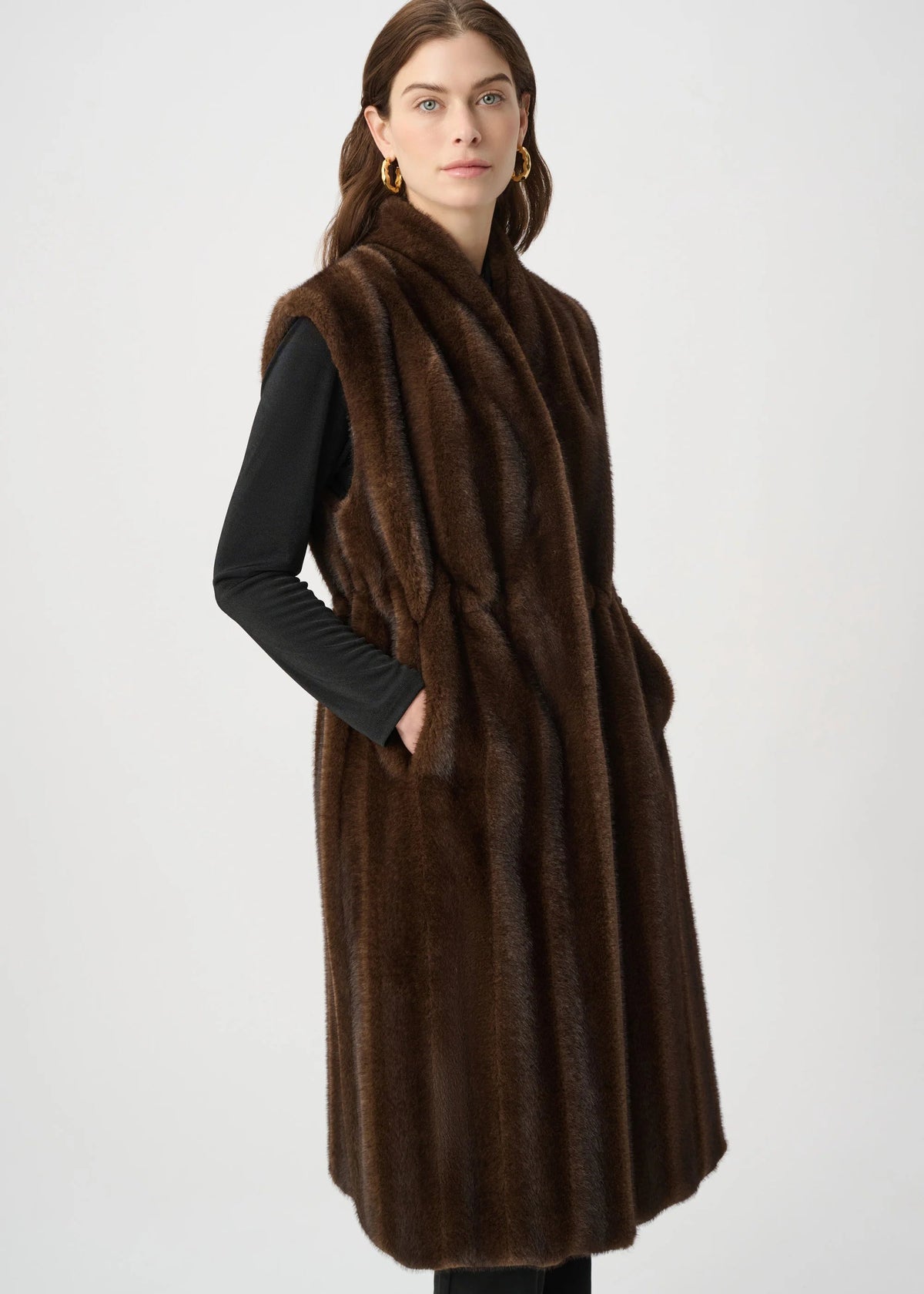 Woman wearing a brown fur vest over a black outfit on a white background
