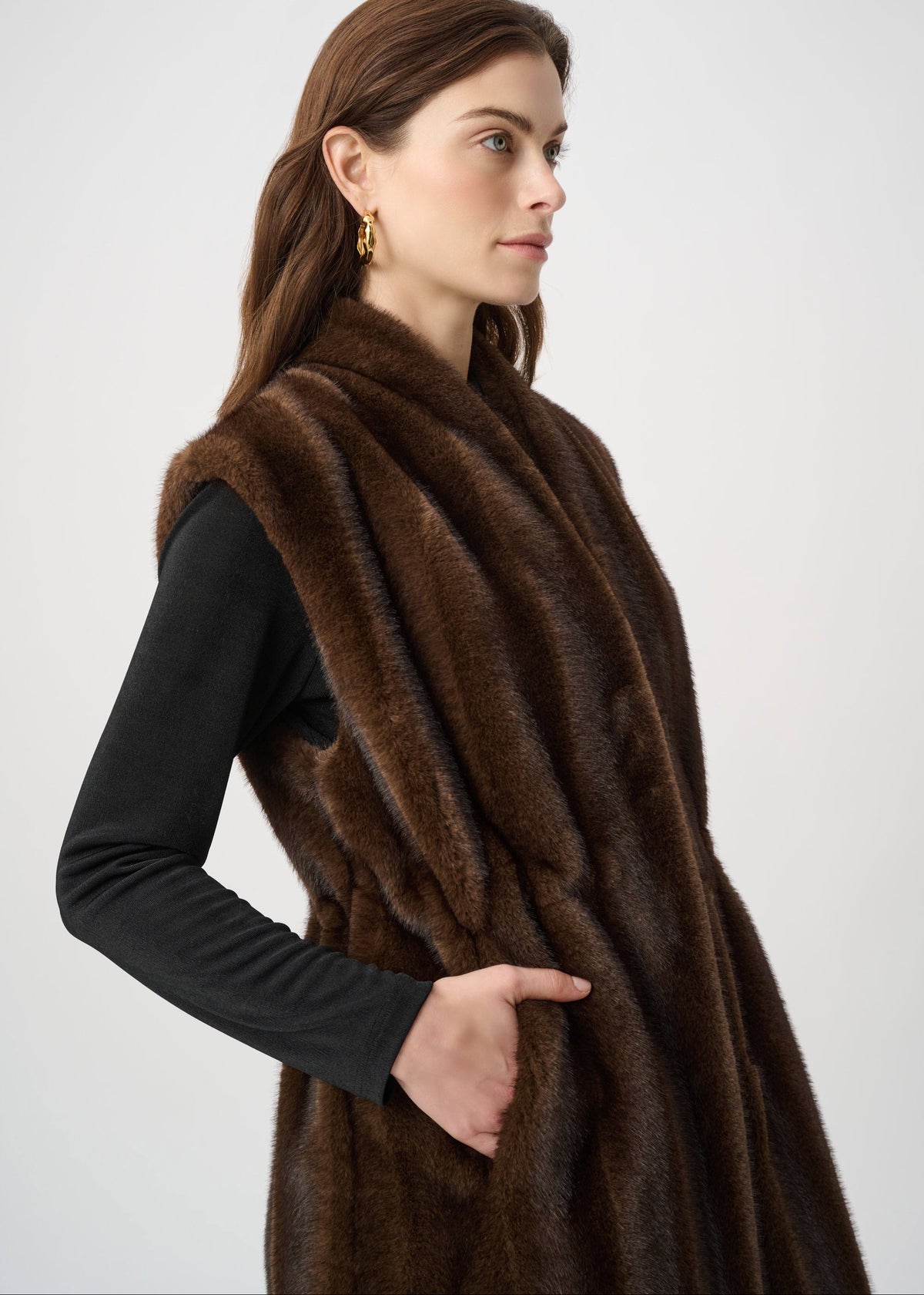 Woman wearing a brown fur vest against a white background