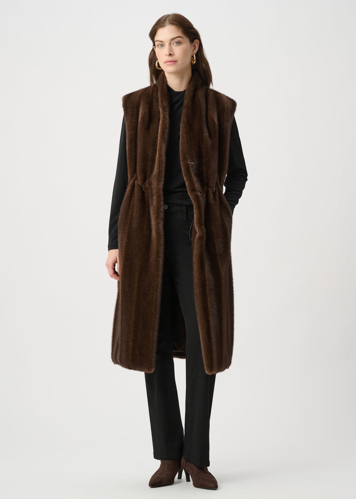 Woman wearing a long brown coat and scarf on a white background