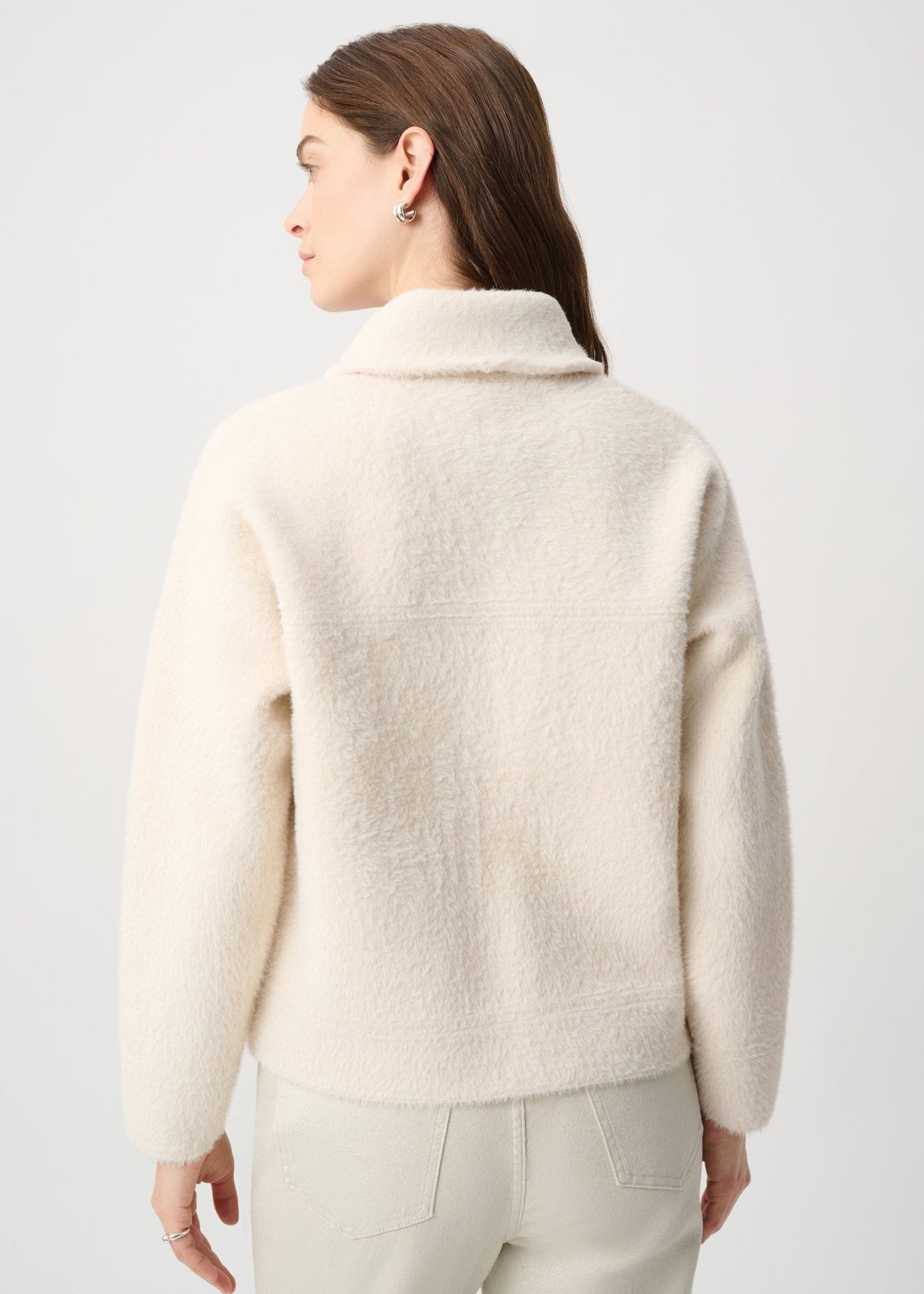 Woman wearing a cream-colored sweater against a white background