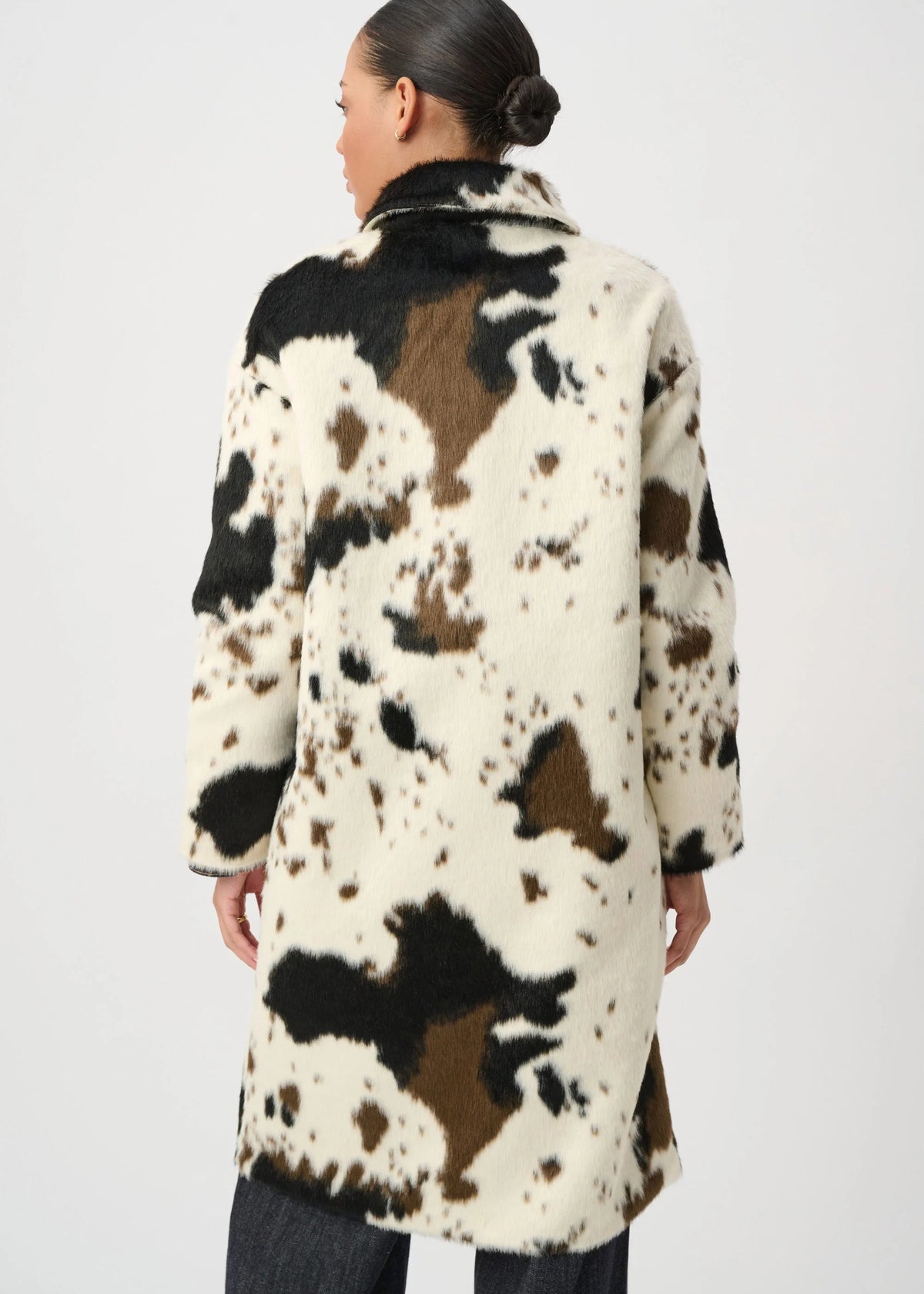 Person wearing a cow print coat on a white background