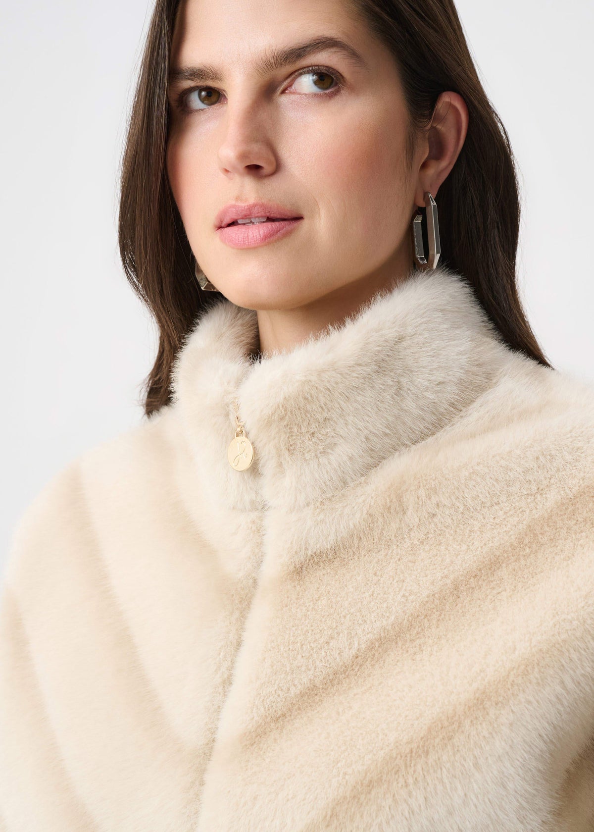 Woman wearing a cream fur coat against a white background
