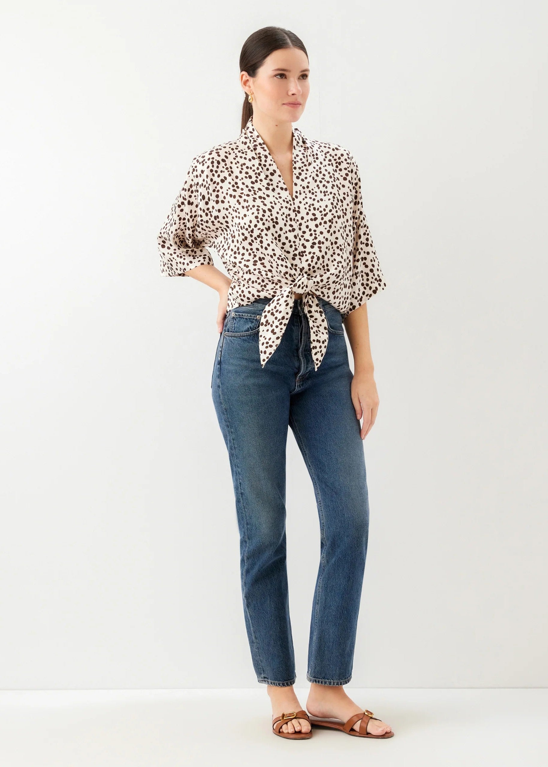 Woman wearing a leopard print blouse and blue jeans on a white background