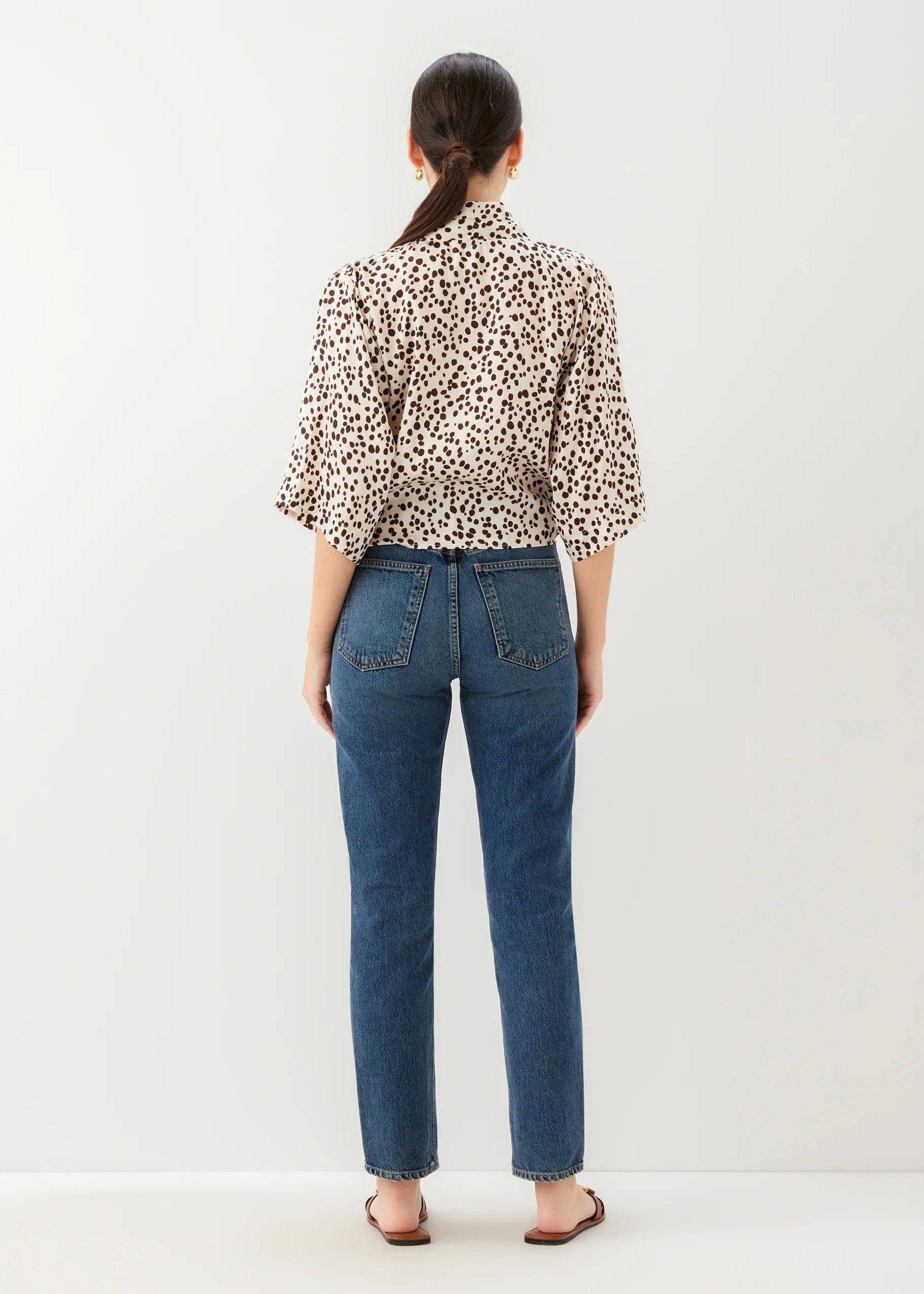 Person wearing a leopard print shirt and blue jeans on a white background