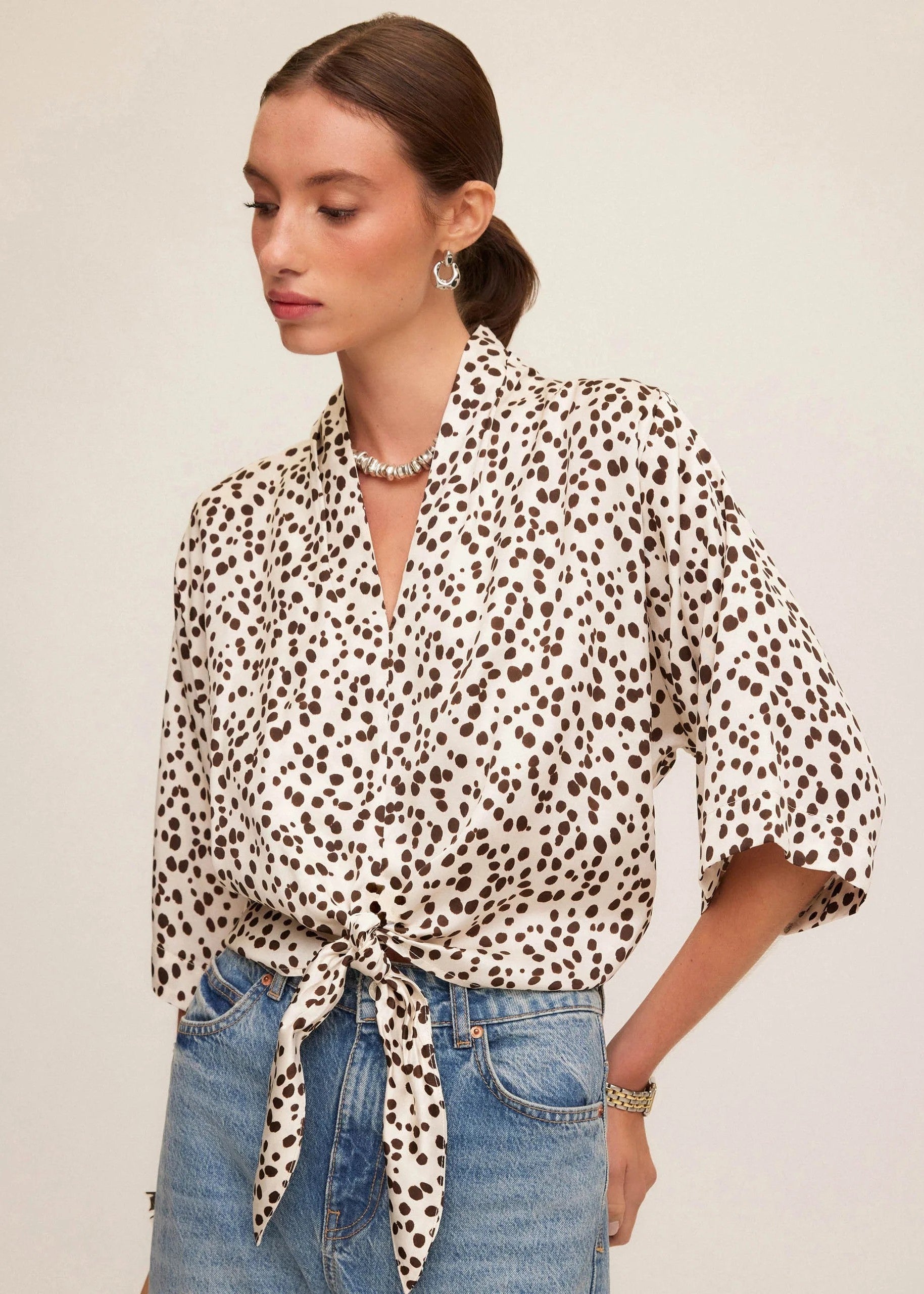 Woman wearing a leopard print blouse and jeans on a beige background