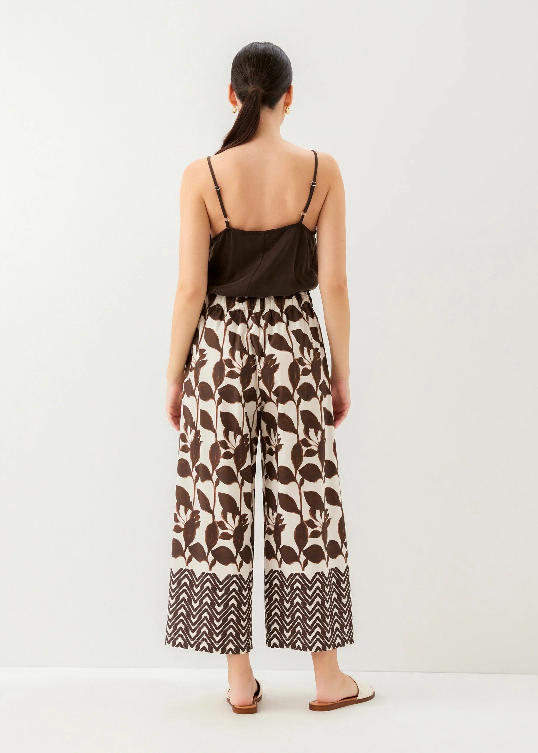Woman wearing a black top and patterned wide-leg pants on a white background