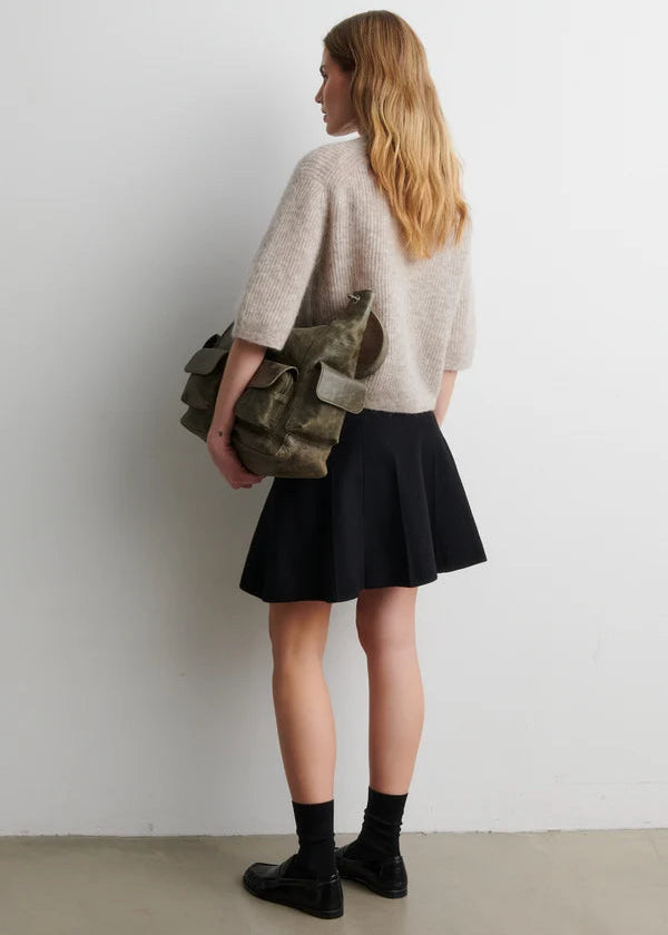 Woman holding a camouflage bag against a plain background