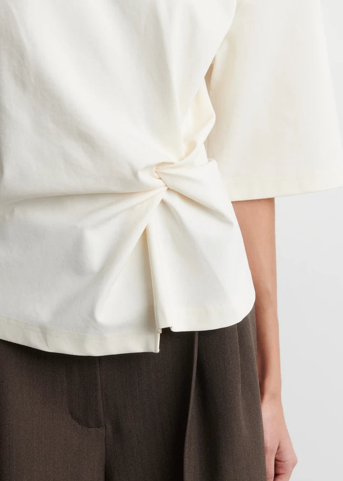 White blouse with a knot detail worn by a person, on a white background