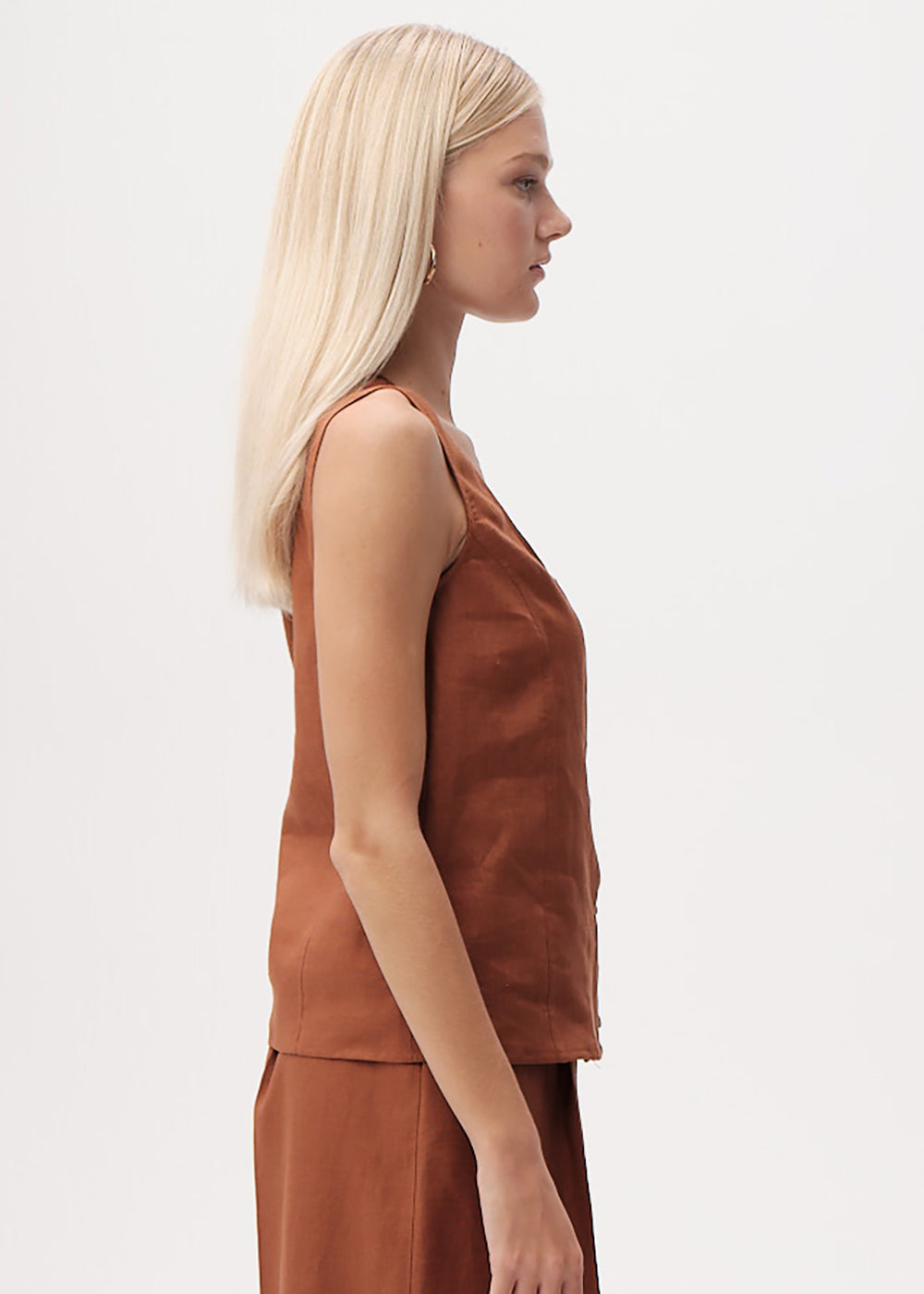 Woman wearing a brown sleeveless top and skirt on a white background