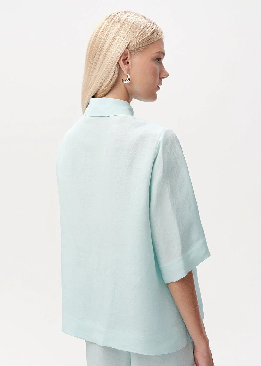 Woman wearing a light blue blouse and pants on a white background
