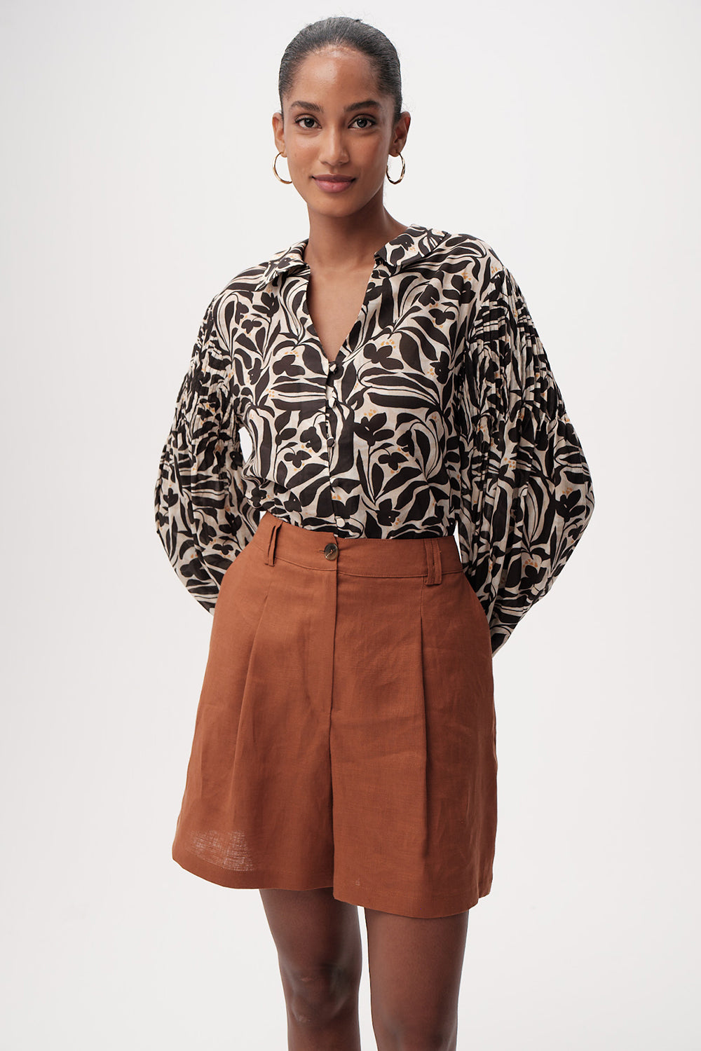 Woman wearing a patterned blouse and brown skirt on a white background