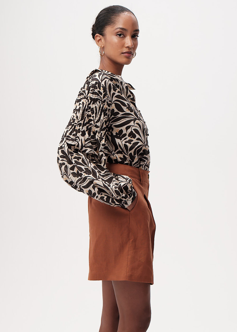 Woman wearing a patterned blouse and brown skirt on a white background