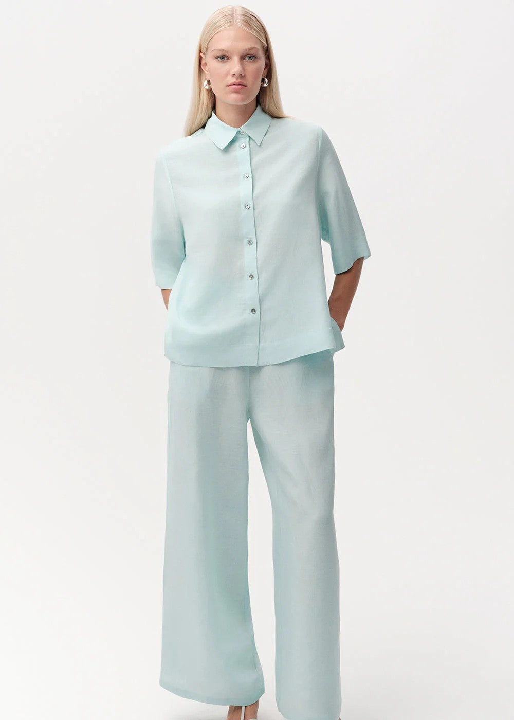 Woman wearing a light blue shirt and pants on a white background