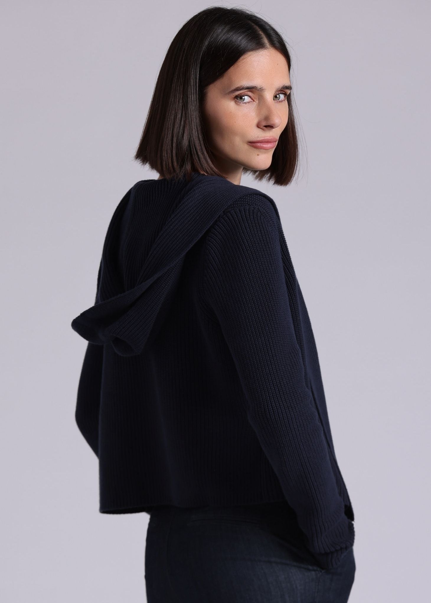 Woman wearing a black sweater against a plain background