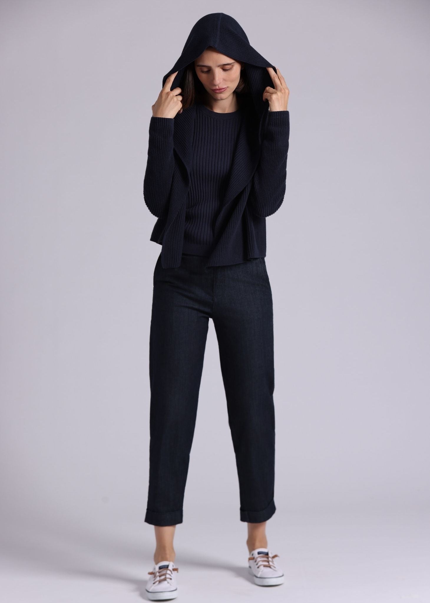 Person wearing a black outfit with a hood against a white background