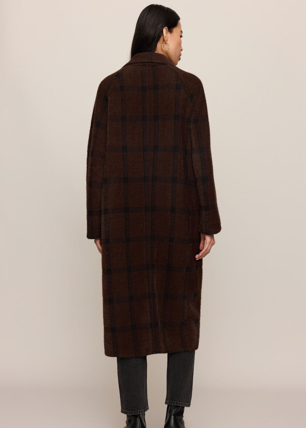 Person wearing a brown checkered coat on a beige background