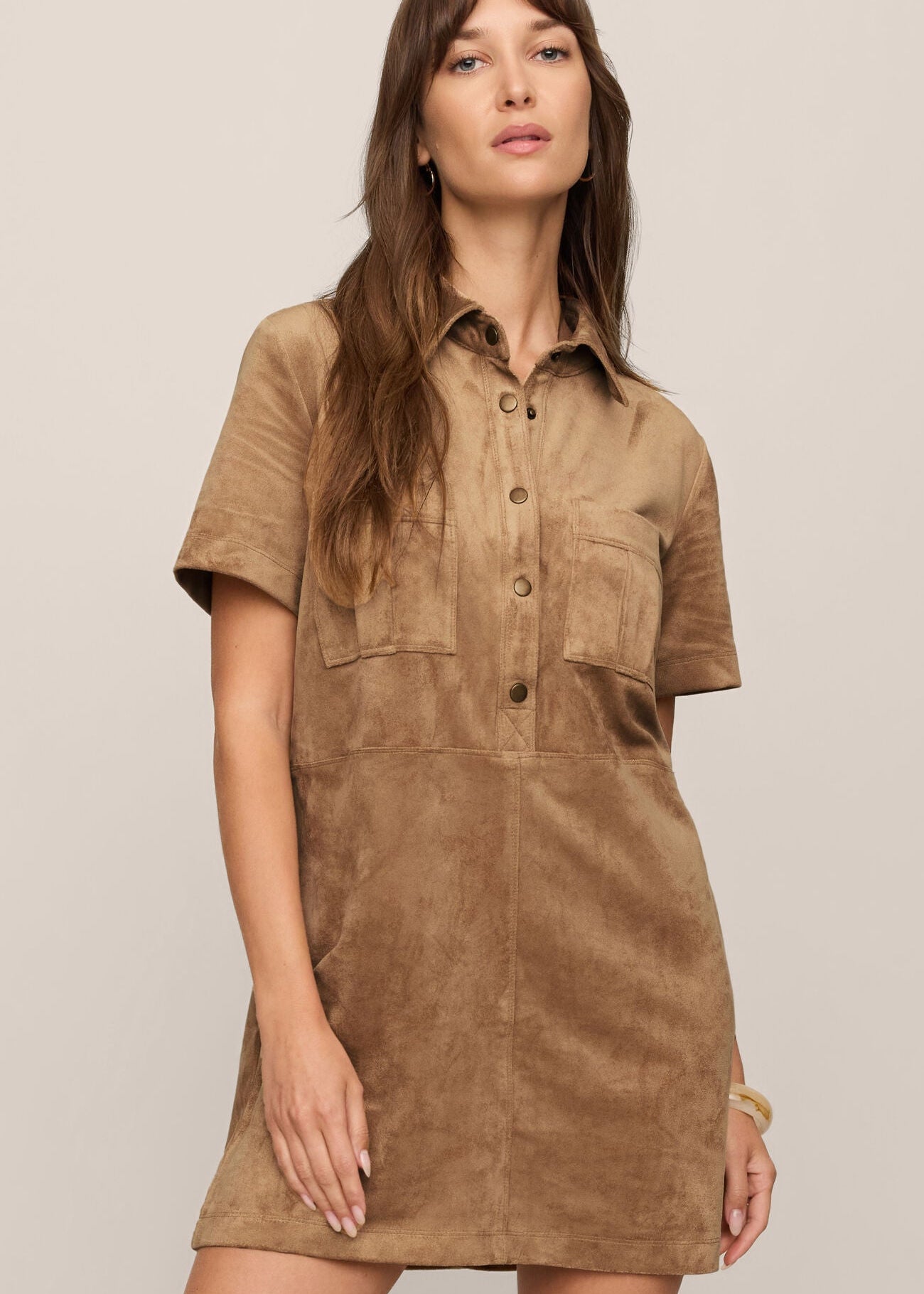 Woman wearing a brown suede dress against a plain background