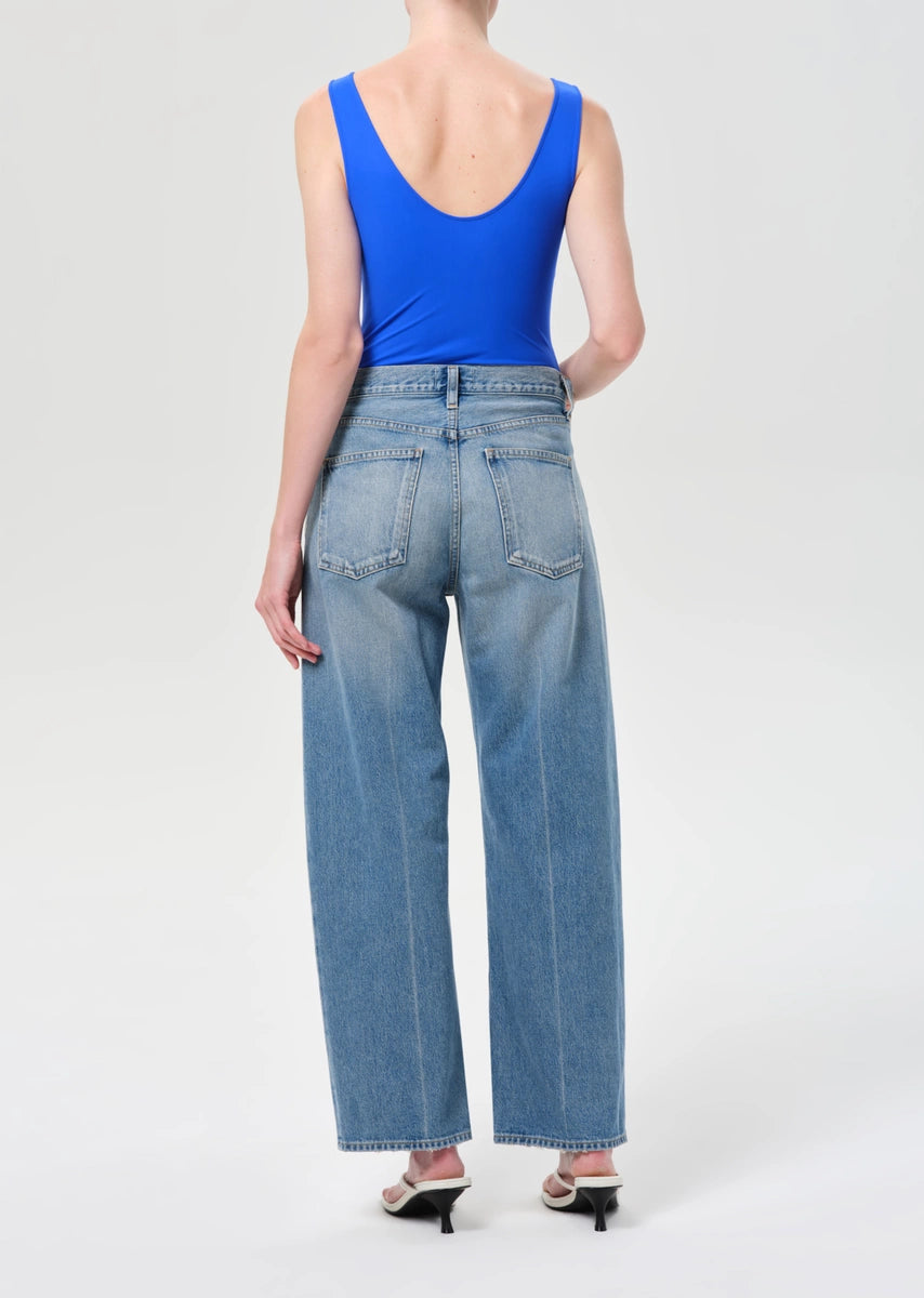 Person wearing a blue tank top and light blue jeans on a white background