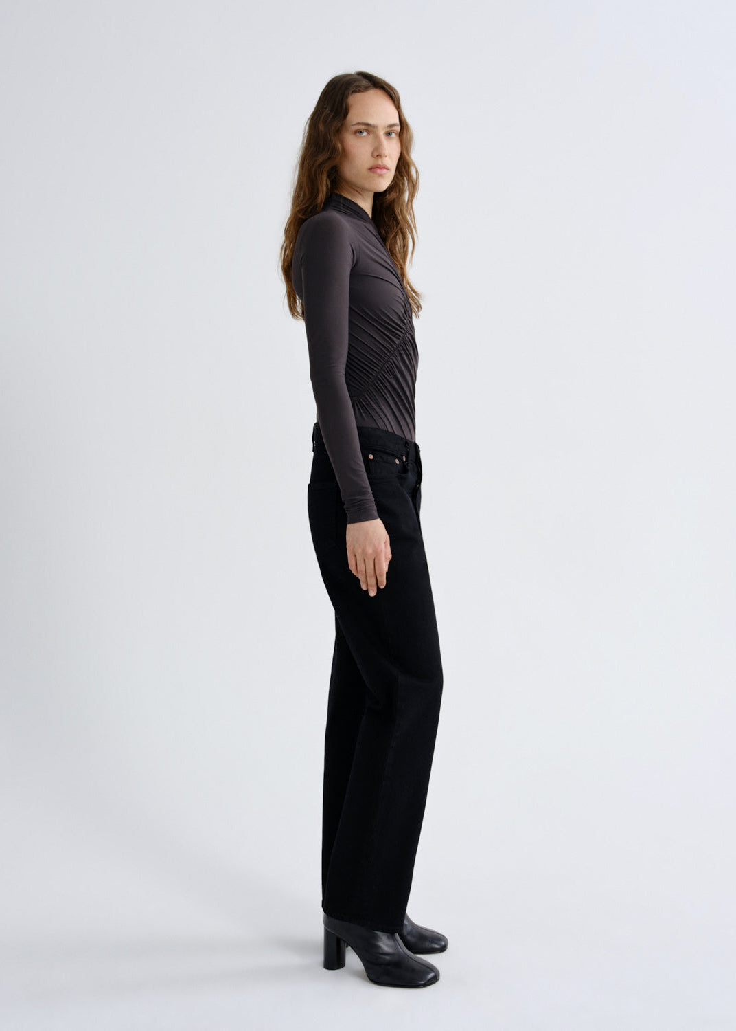 Woman wearing a black long-sleeve top and black pants on a white background