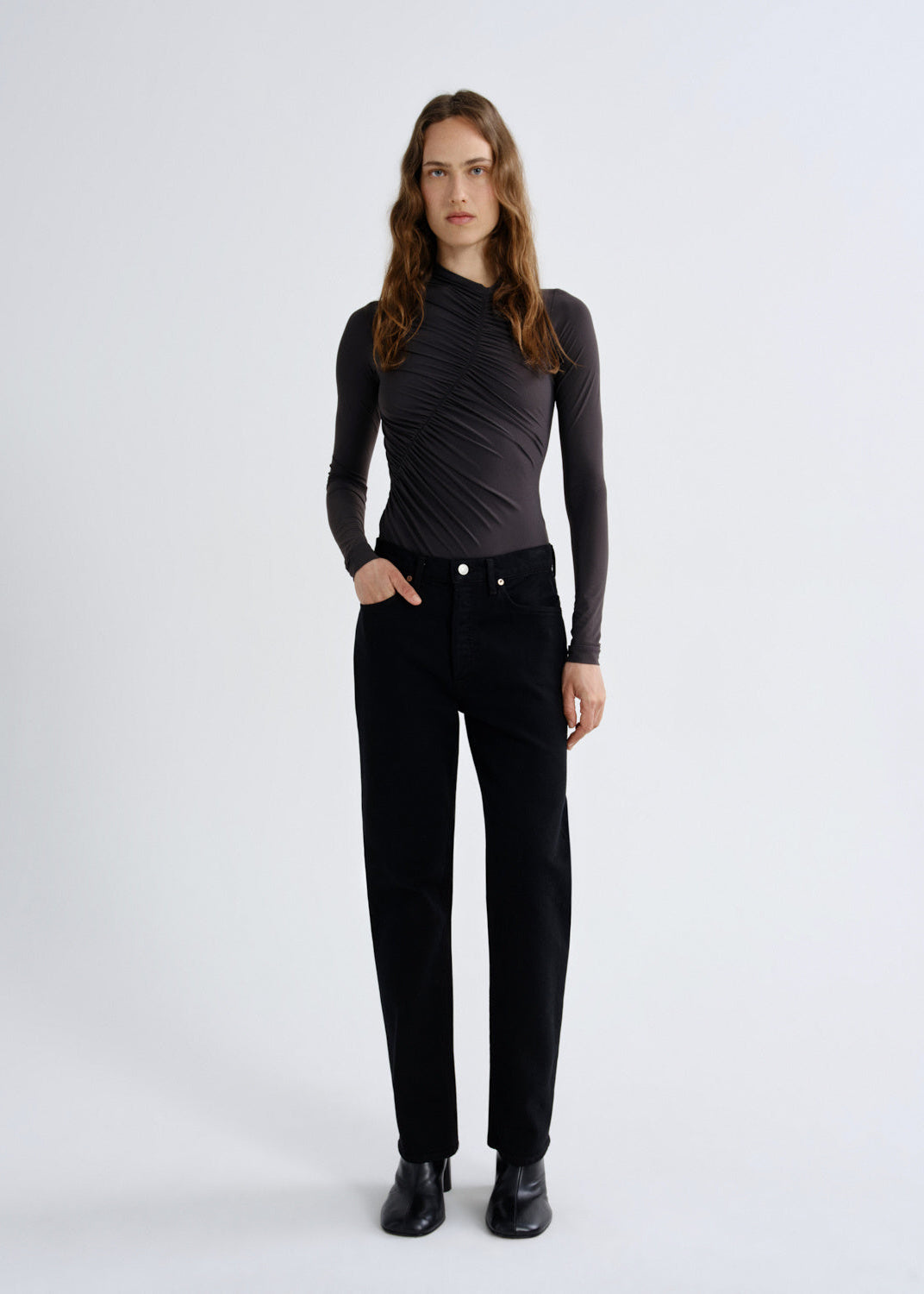 Woman wearing a black long-sleeve top and black pants on a white background